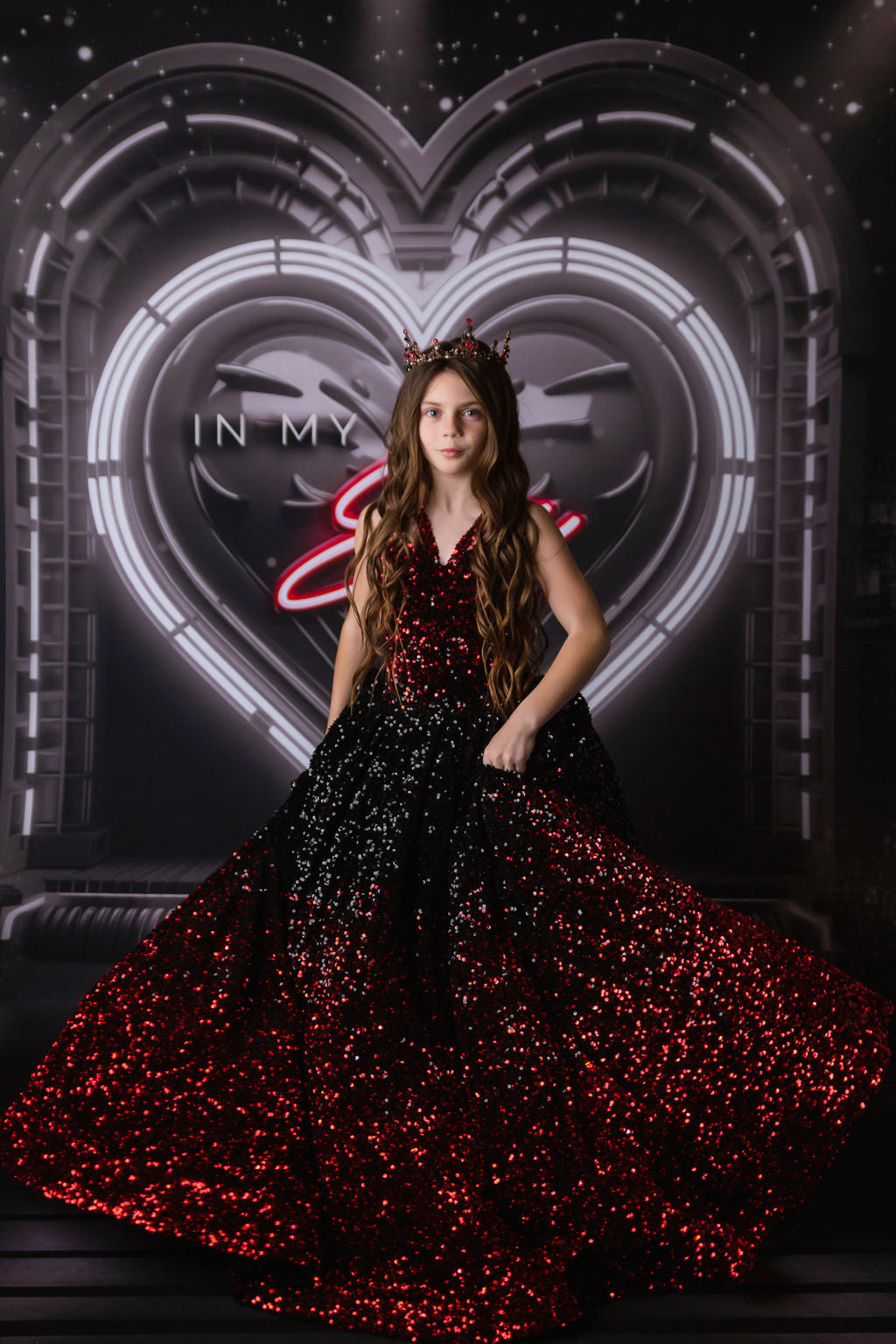 Little girl in a shimmering gown, reminiscent of Taylor Swift’s iconic red carpet glamour, crowned and posing fiercely.
