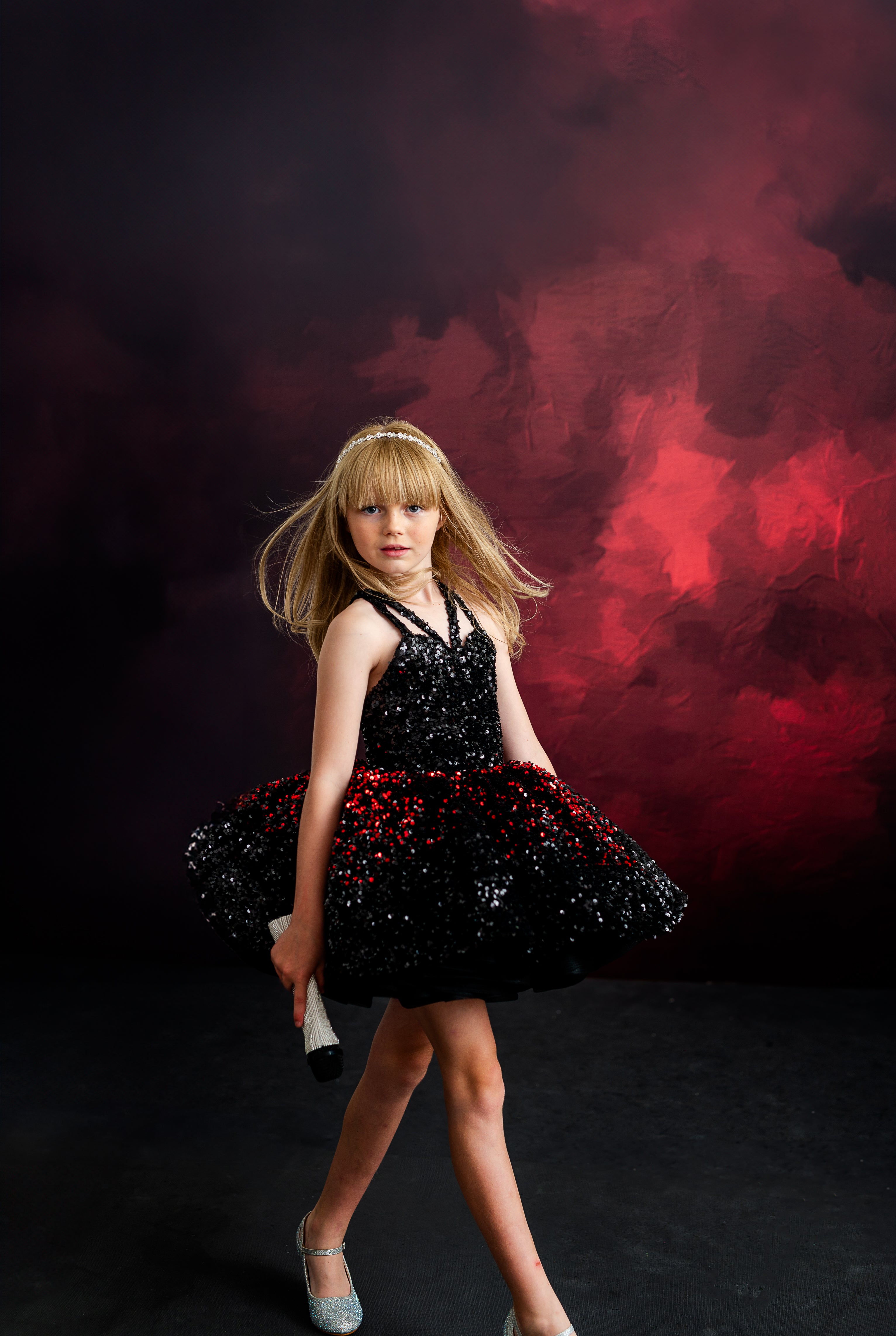 Child in a glamorous gown with a tiara, evoking Taylor Swift’s signature blend of elegance and edge in a red and black sequin design.