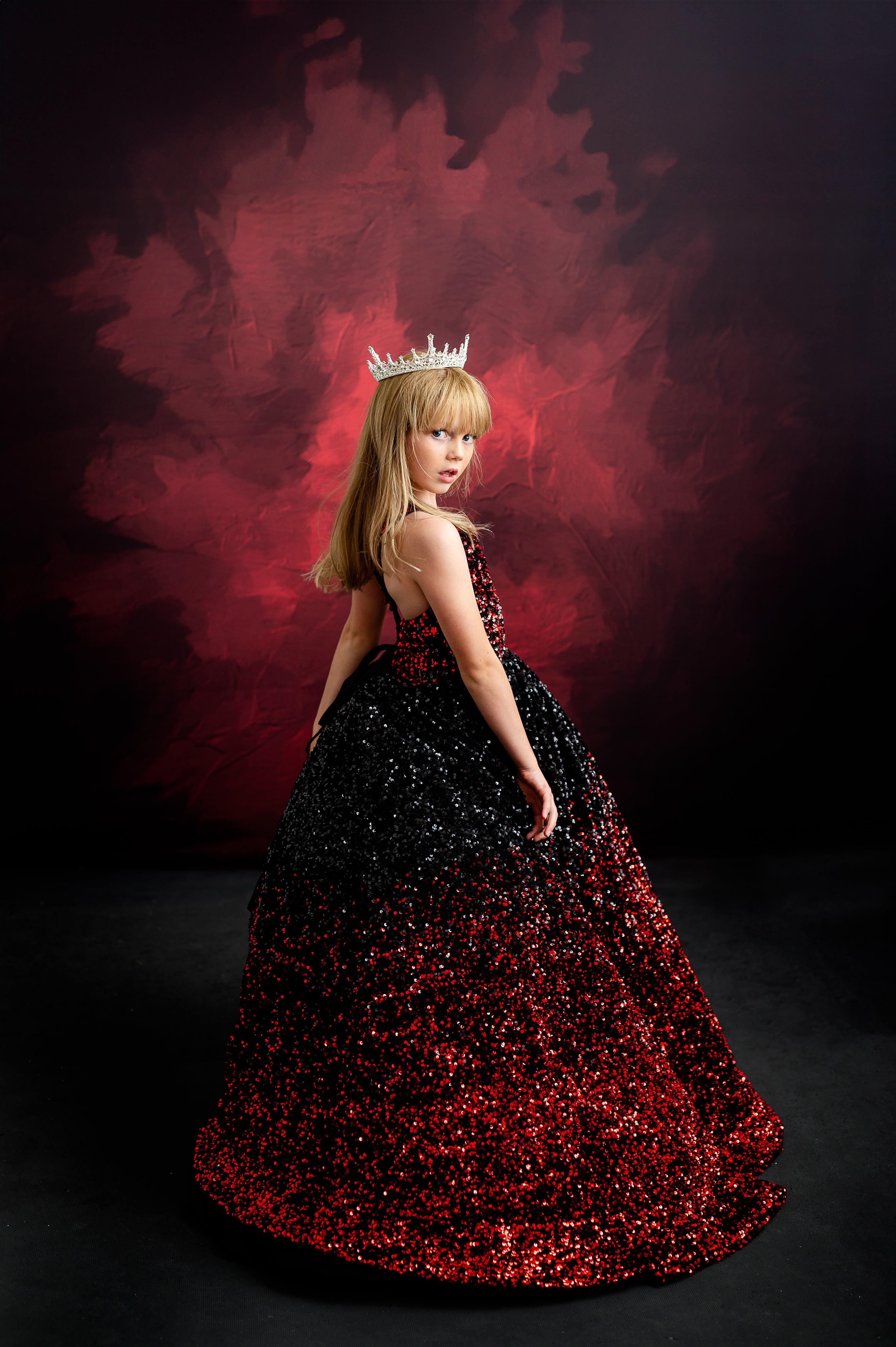 Young girl twirling in a dazzling gown, channeling Taylor Swift's signature blend of elegance and confidence with a royal crown.
