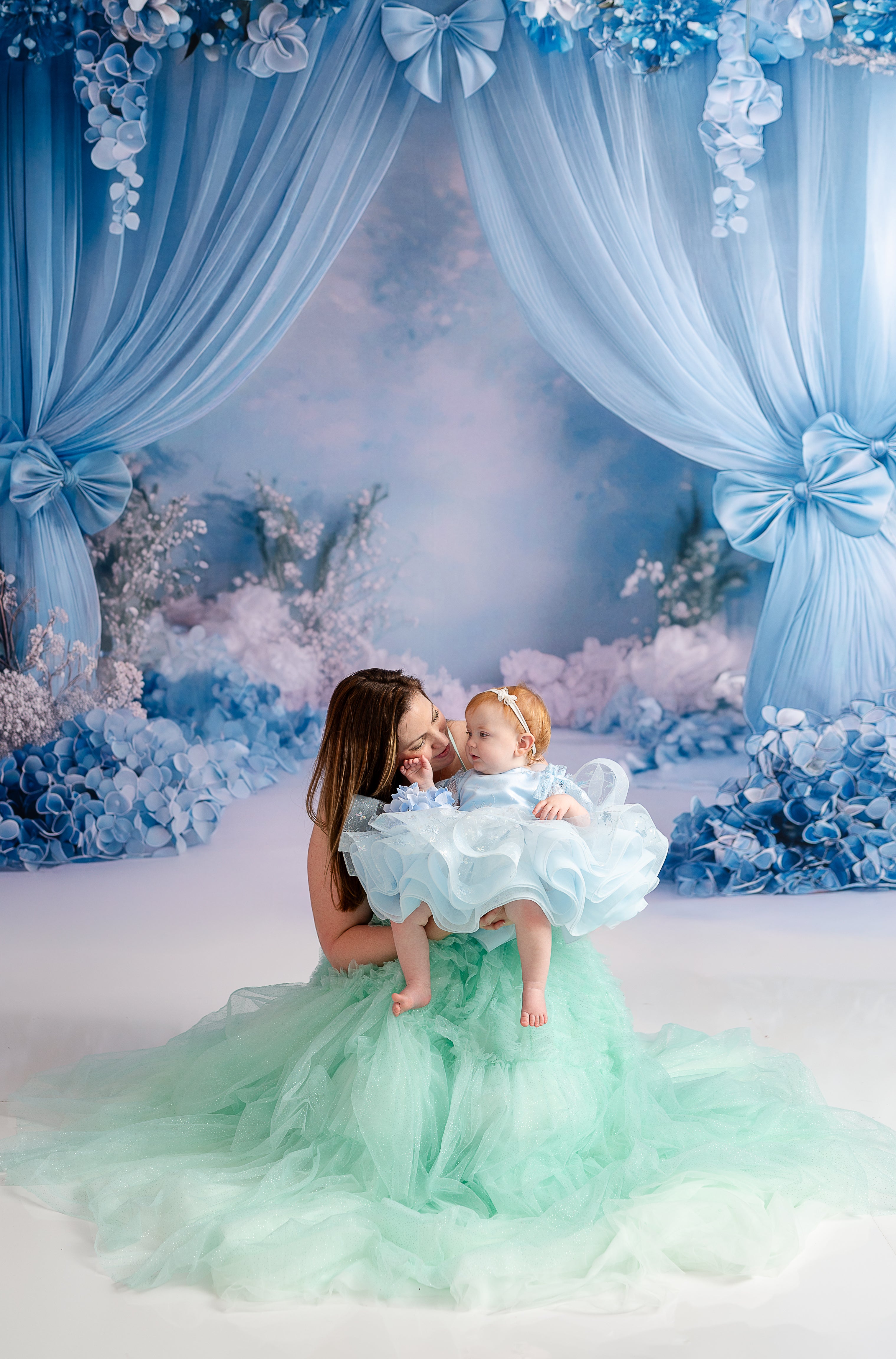 A pair of coordinating gowns create a magical mother-daughter moment in a styled photography session.