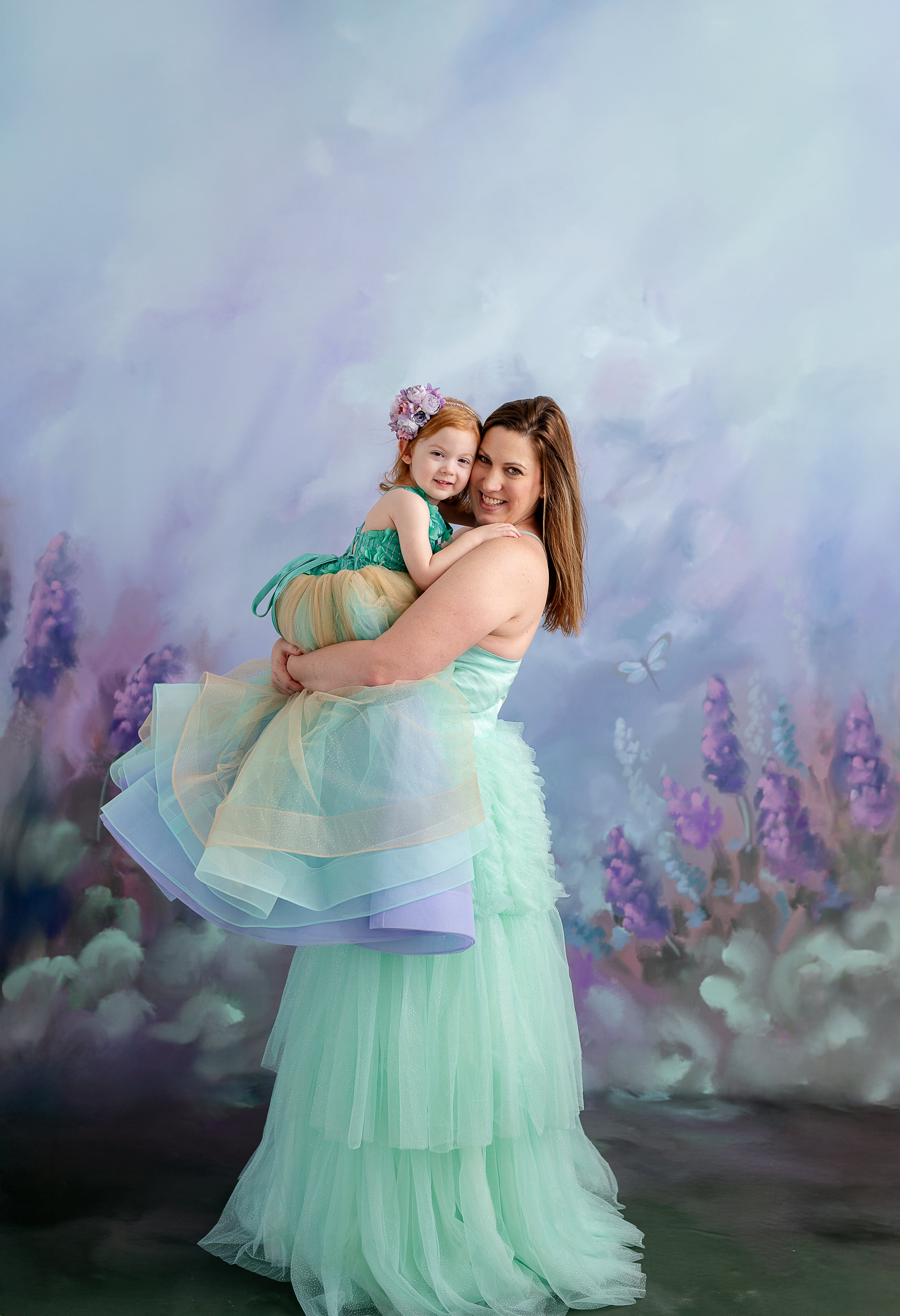 A woman and a little girl share a sweet moment, dressed in complementary pastel dresses with layers of tulle.