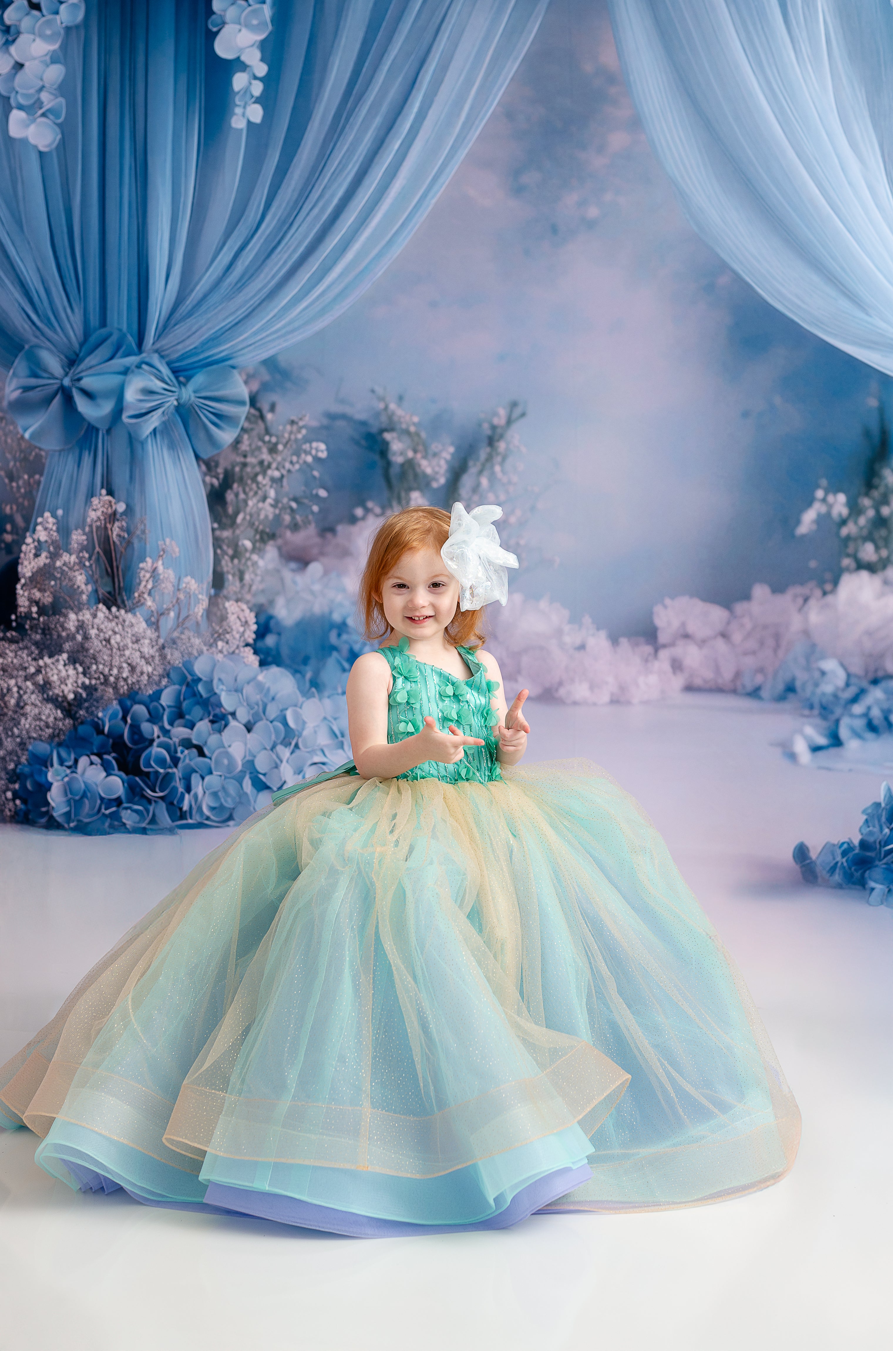 Side view of the toddler gown showcasing its voluminous layered tulle skirt in shades of aqua and gold.
