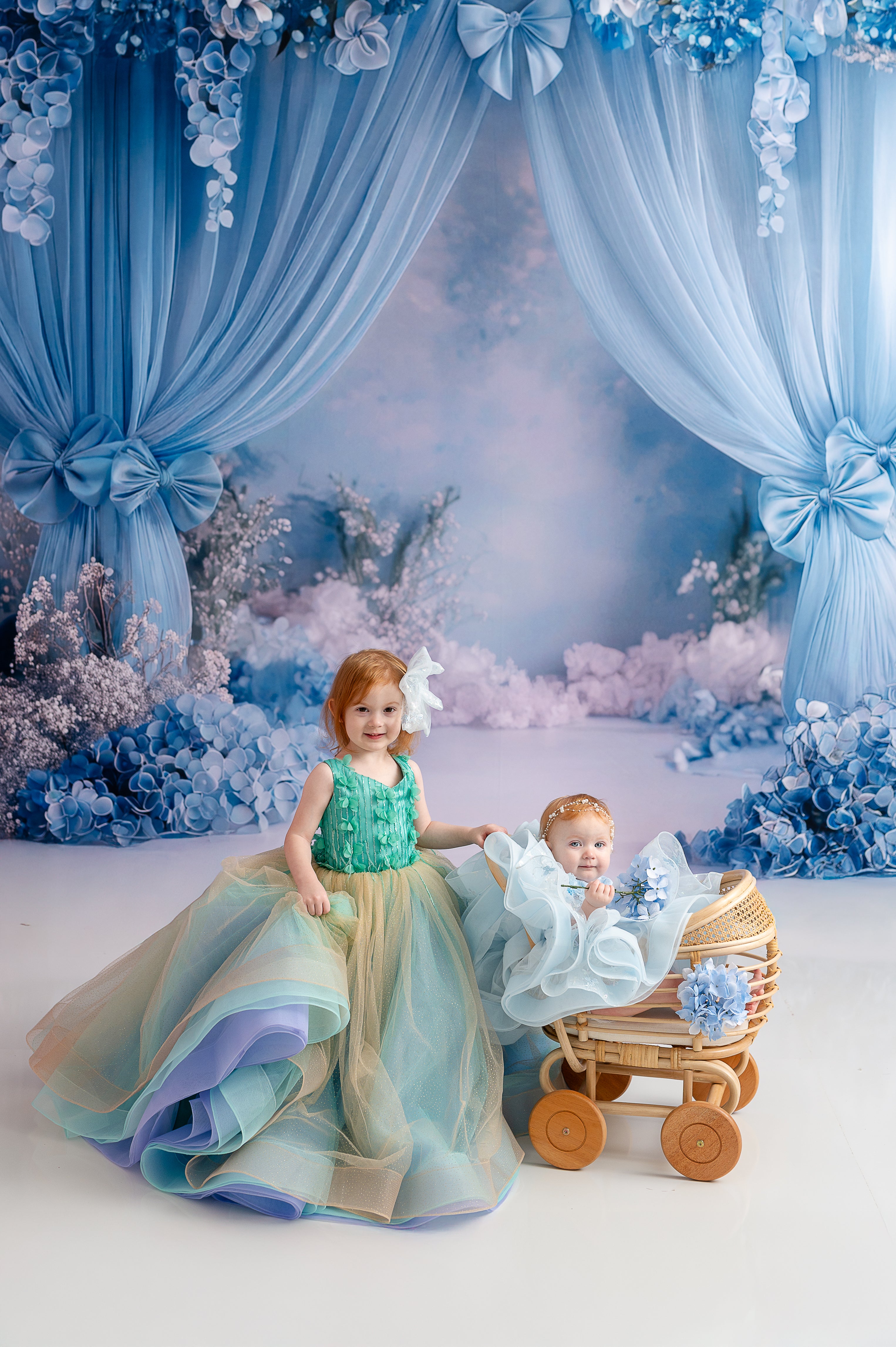 A young girl in an aqua and gold tulle gown twirling gracefully in a whimsical blue floral backdrop.