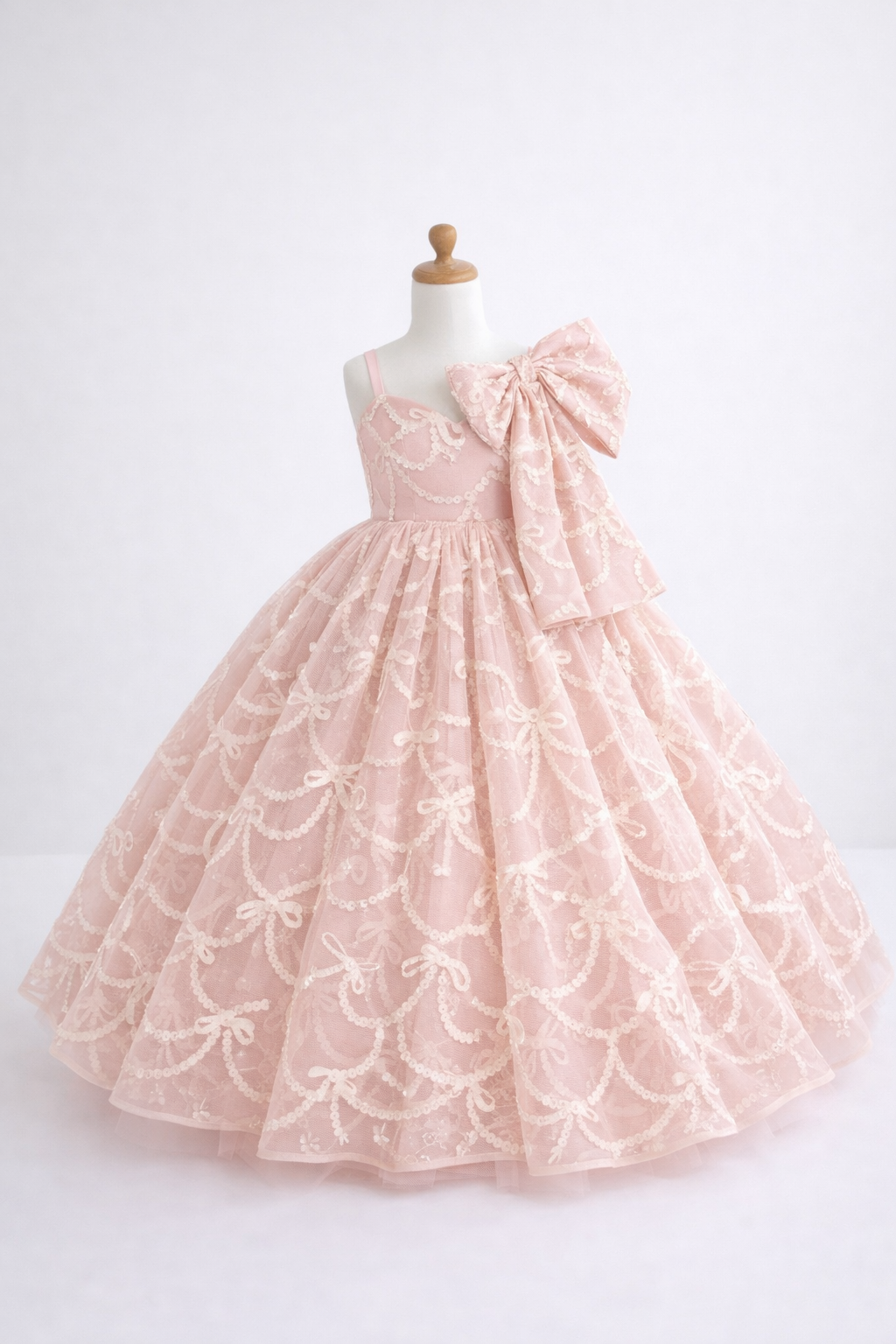 Pink lace dress with a large bow on a mannequin against a white background