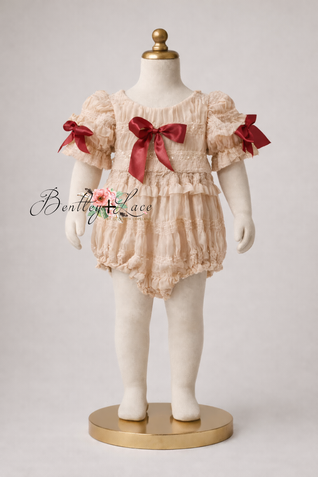 Children's outfit with ruffled top and bloomers on a mannequin against a plain background.