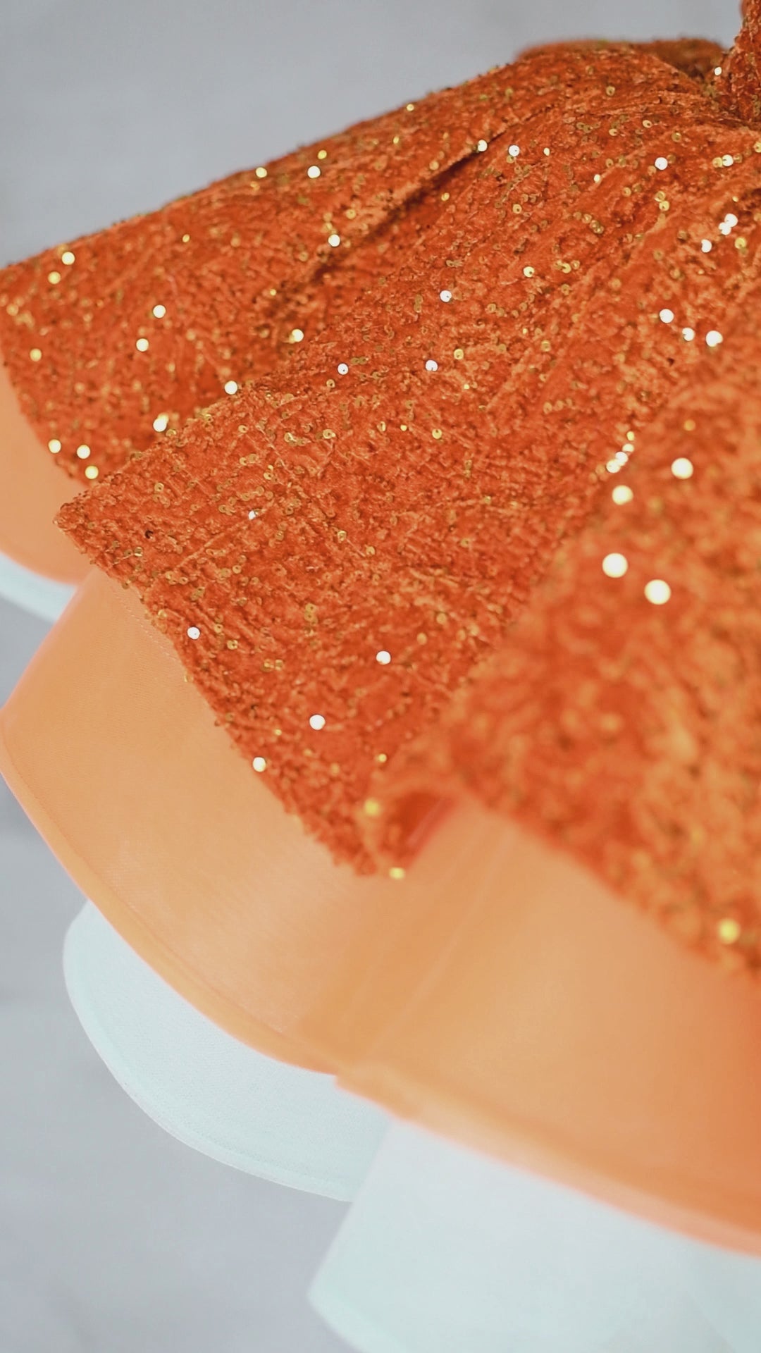 Close-up of orange sequin bodice with layered organza and tulle skirt on Sparkling Starlet Couture Dress.