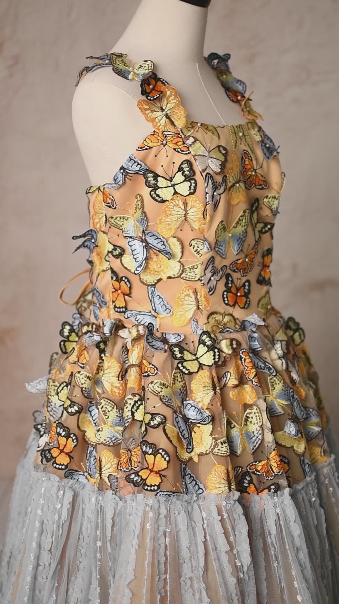 A vibrant butterfly-adorned gown with a golden bodice and cascading layers of airy blue tulle.