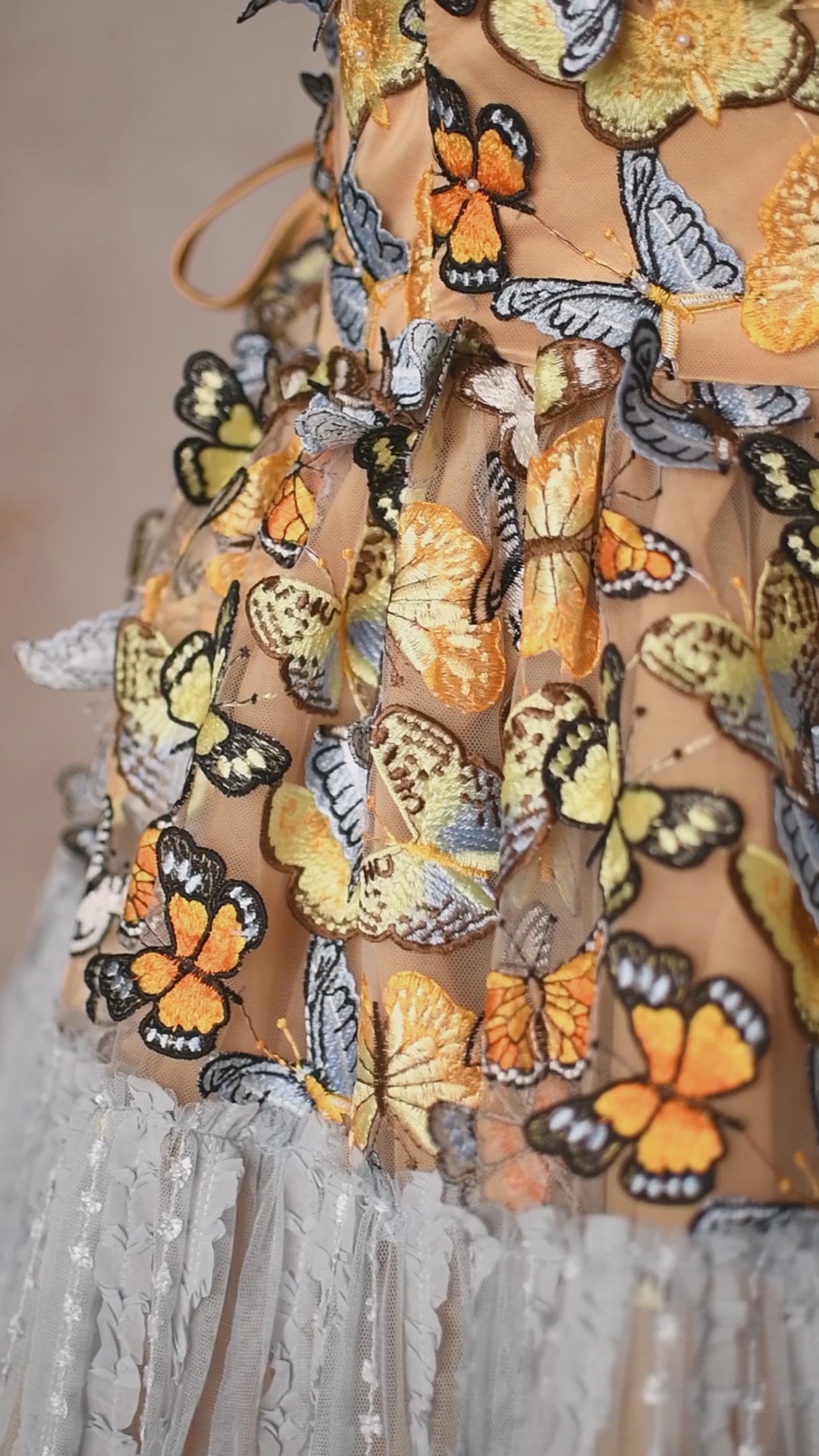 A whimsical gown featuring a butterfly-themed bodice and a textured, tiered skirt in soft hues.