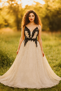 Woman in a black and white dress standing in a field with a blurred background