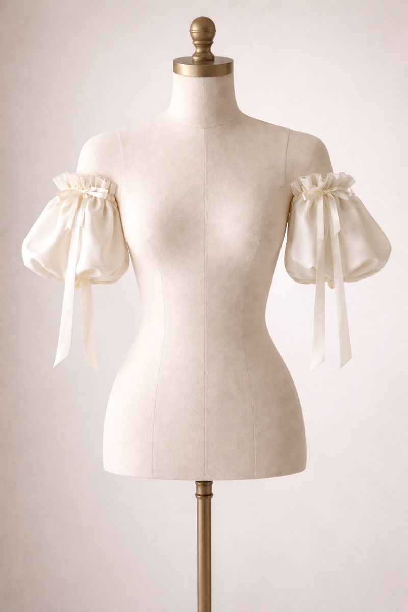 Mannequin wearing a cream-colored dress with sheer sleeves on a plain background