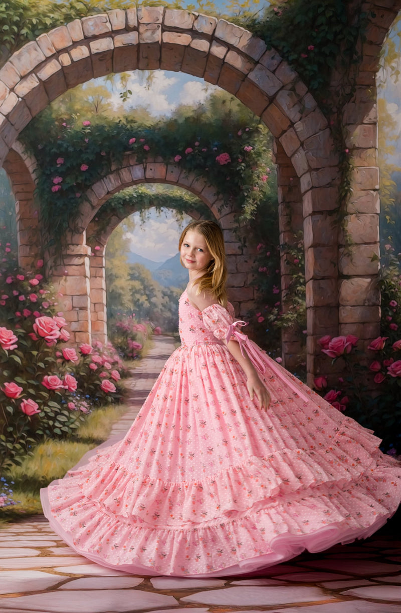 Woman in a pink dress standing under a stone archway with floral decorations