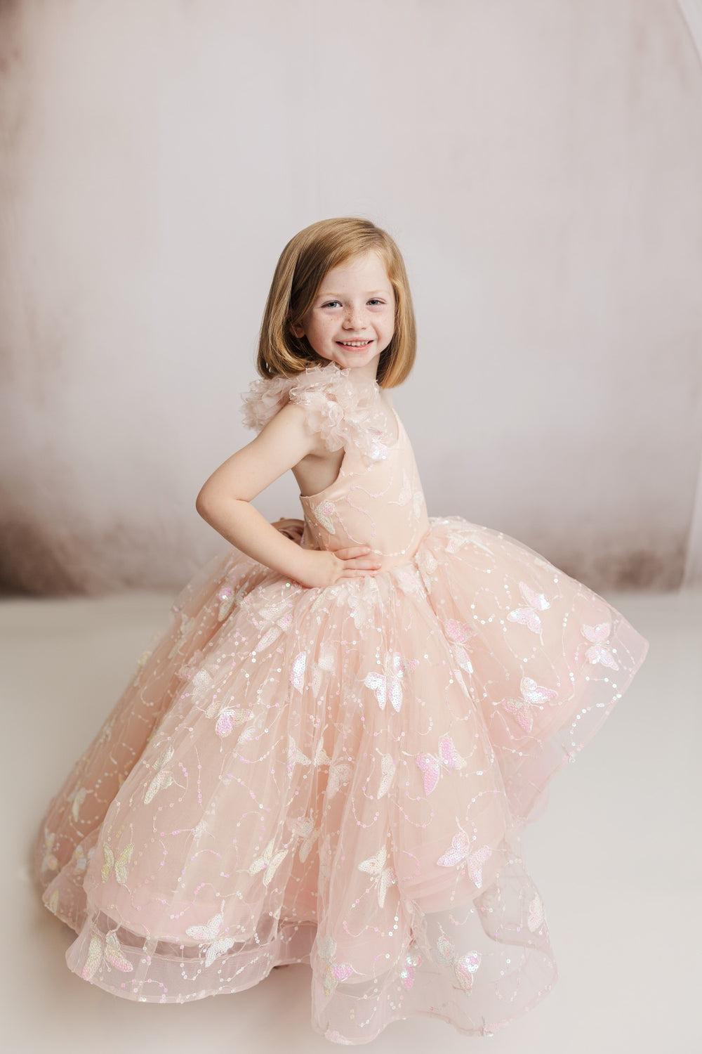 "The Anastasia high-low gown, featuring a stunning 3D sequin embroidered butterfly fabric and a one-shoulder ruffle detail."

