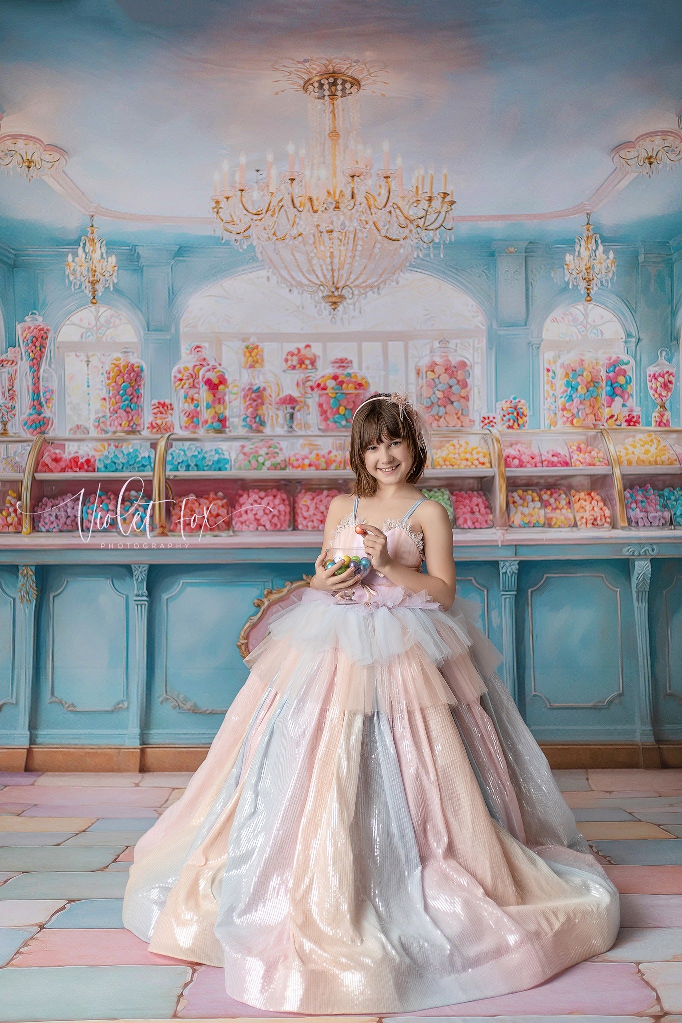 Girl wearing a ombre rainbow themed gown with a candy themed backdrop