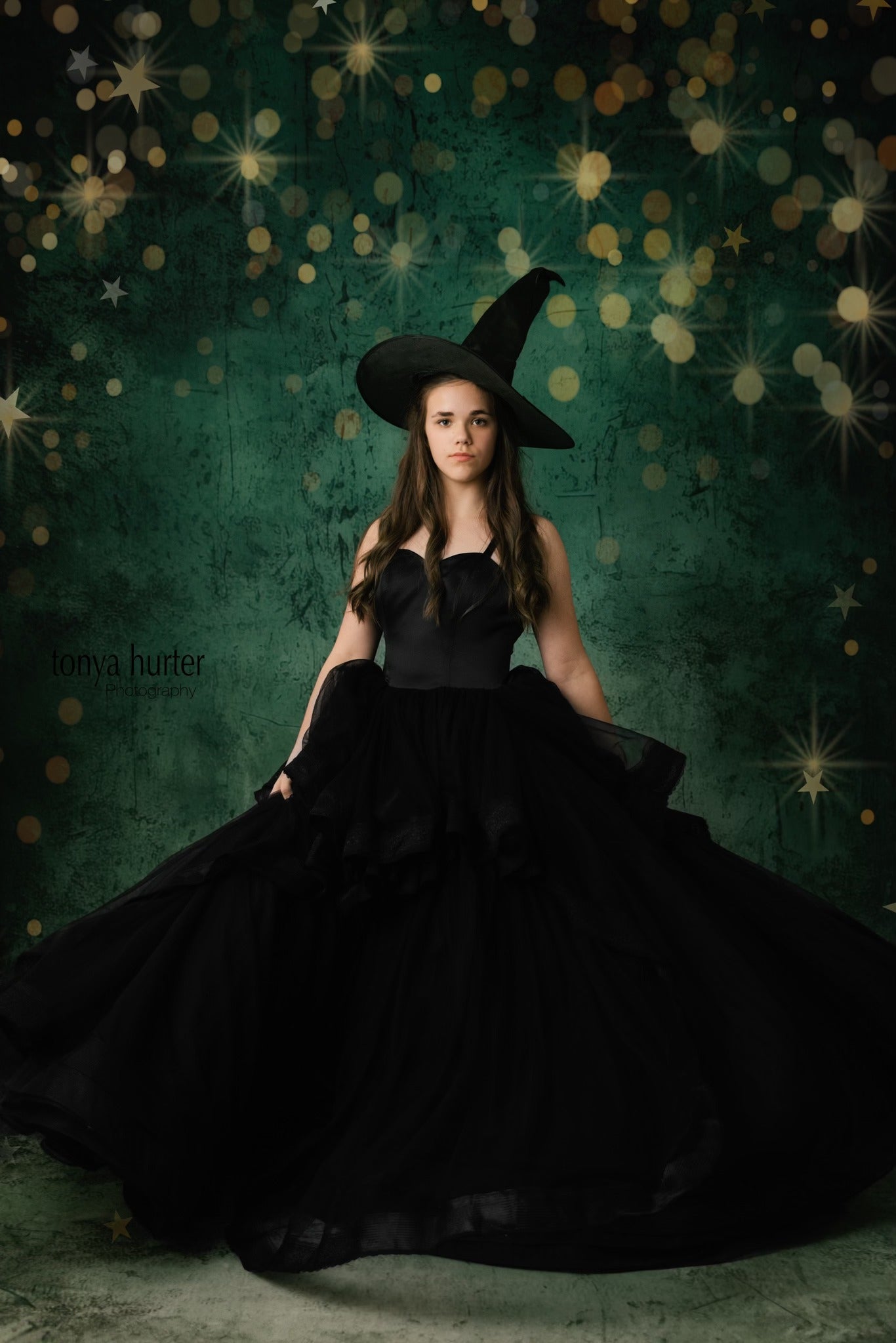 "Young girl in a classic black gown with a flowing skirt and intricate lace detailing on the bodice."
