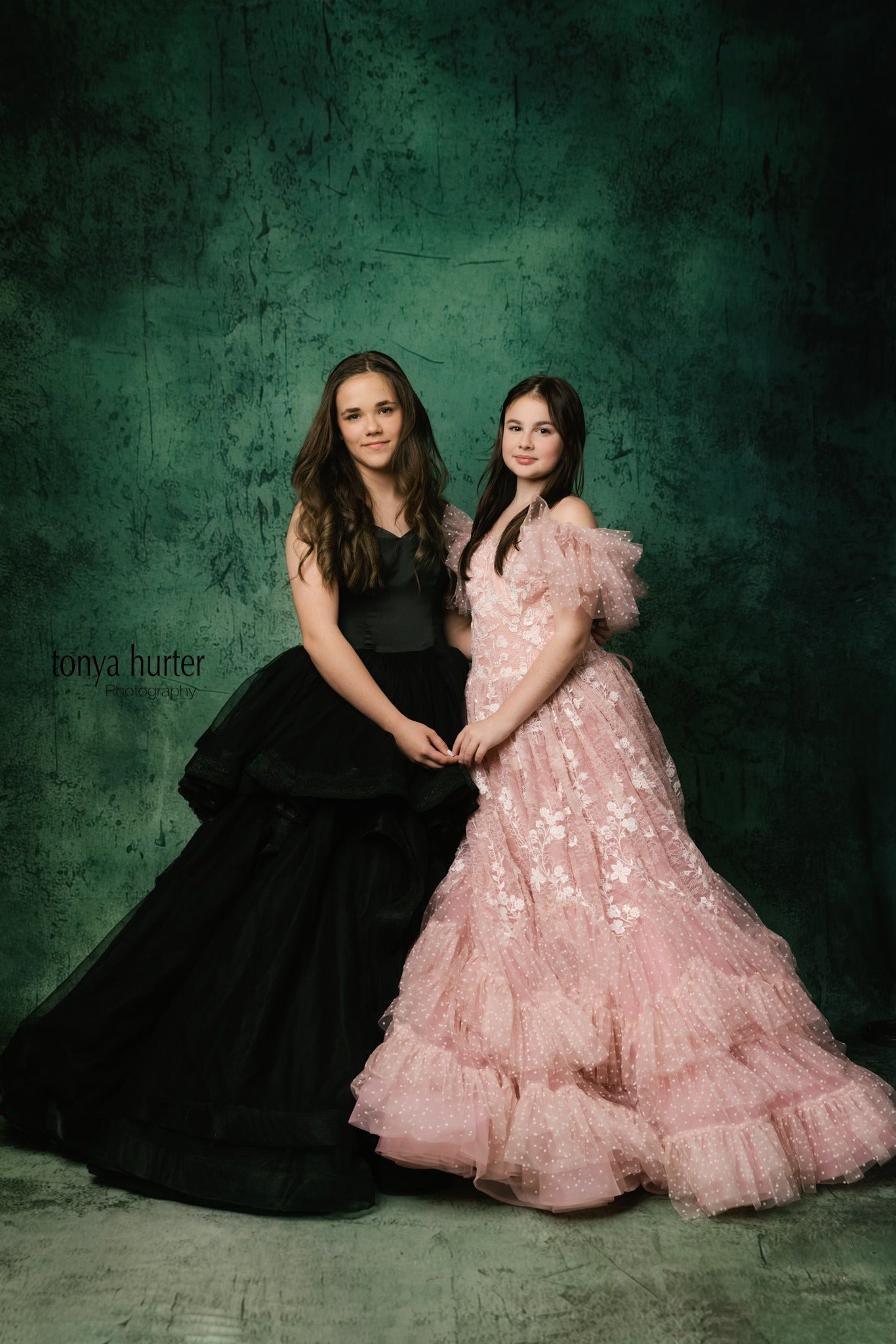 "Full-length view of a girl wearing a black satin gown with a structured bodice and delicate tulle layers."
