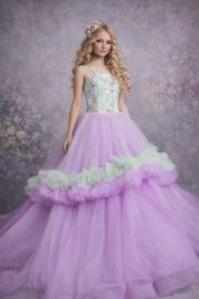 Woman wearing a purple and green gown with floral details against a floral background