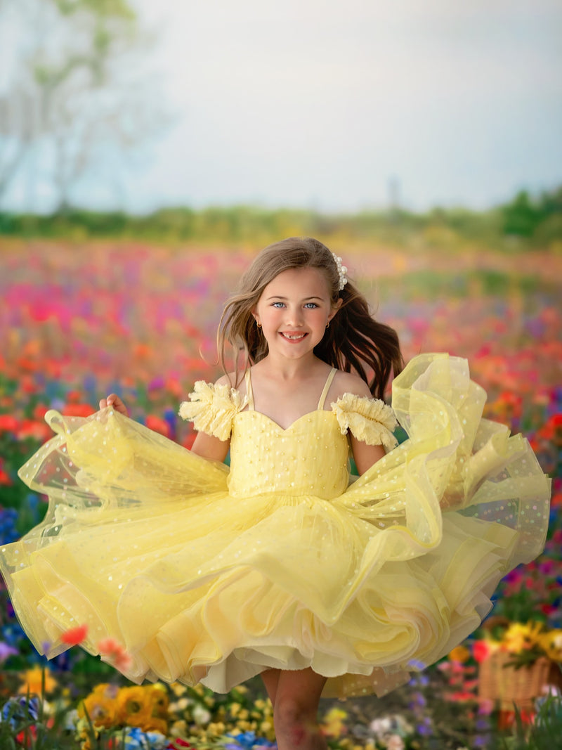 Young girl in a yellow dress standing in a field of flowers