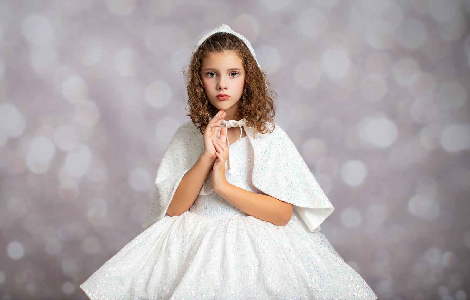 Young girl in a white dress with a hood against a blurred background