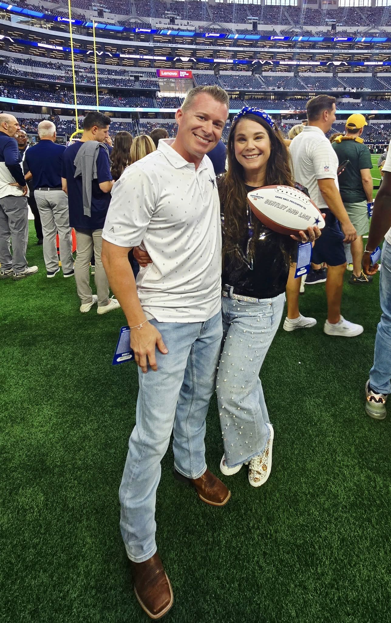 Two people on a football field with one holding a football