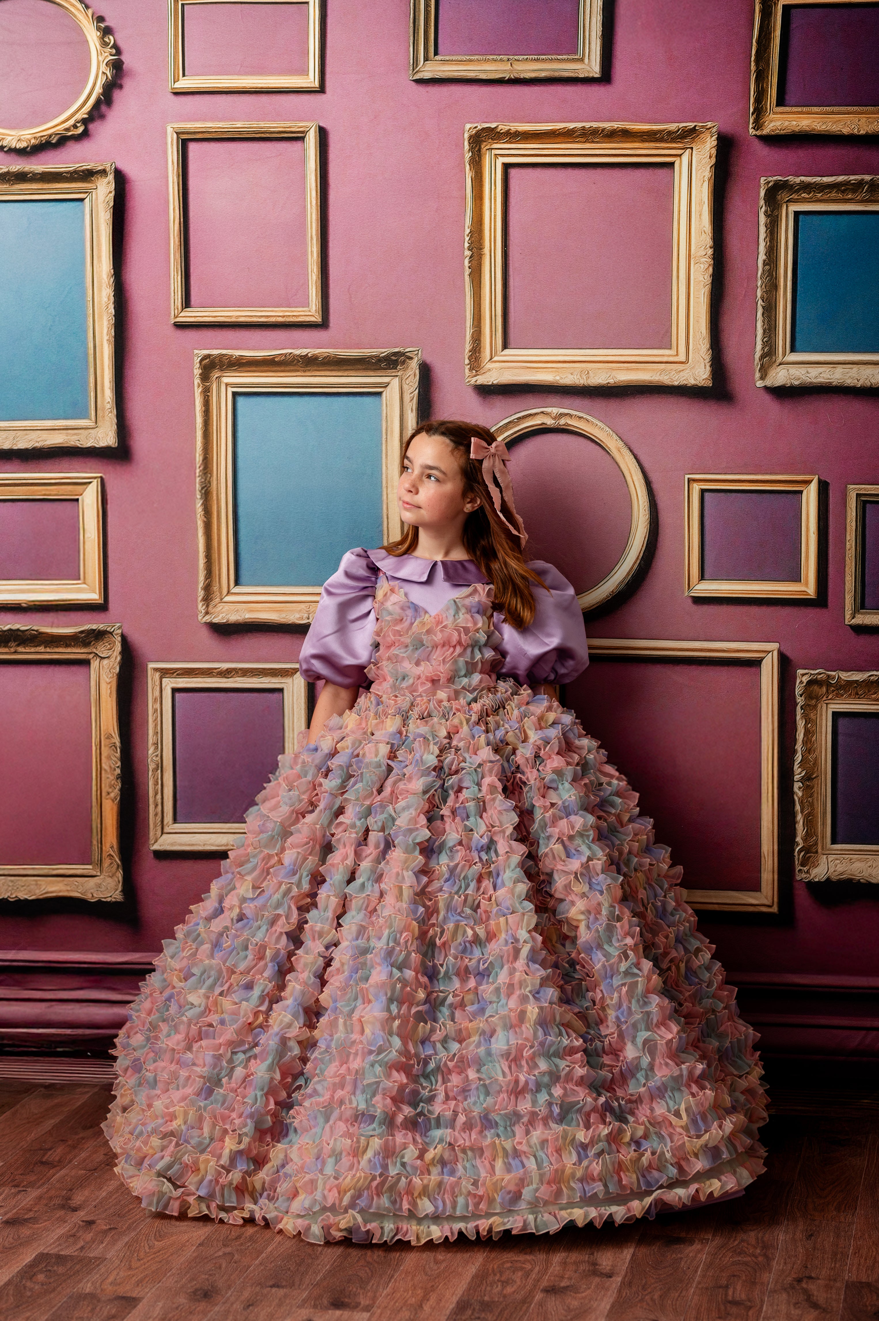 Woman in a vintage dress standing against a wall with framed pictures
