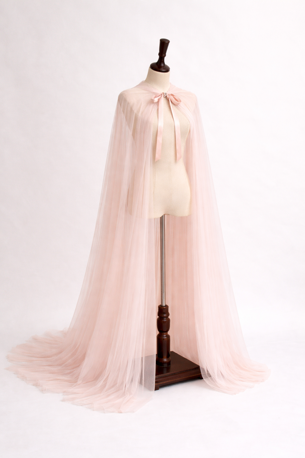 Mannequin wearing a light pink cape on a white background