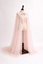 Mannequin wearing a light pink cape on a white background
