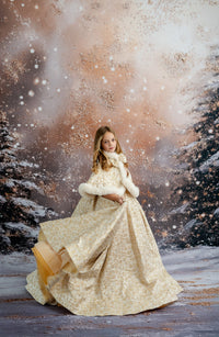 Young girl in a gold brocade holiday gown posing in front of a festive Christmas backdrop with pine garlands and red poinsettias.

