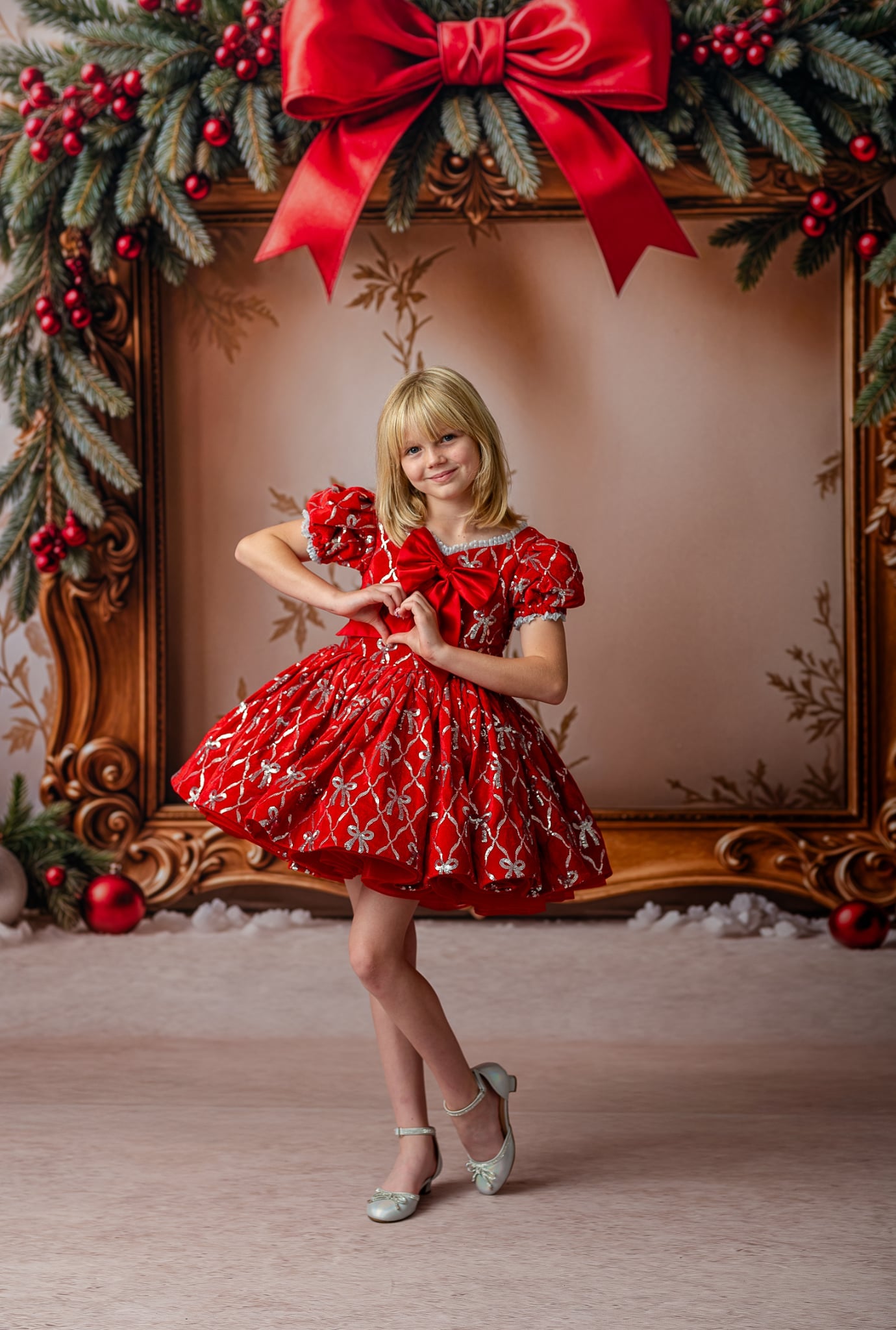 Close-up of red sequin bow details and silver embroidery on the velvet dress bodice with satin bow accent.

