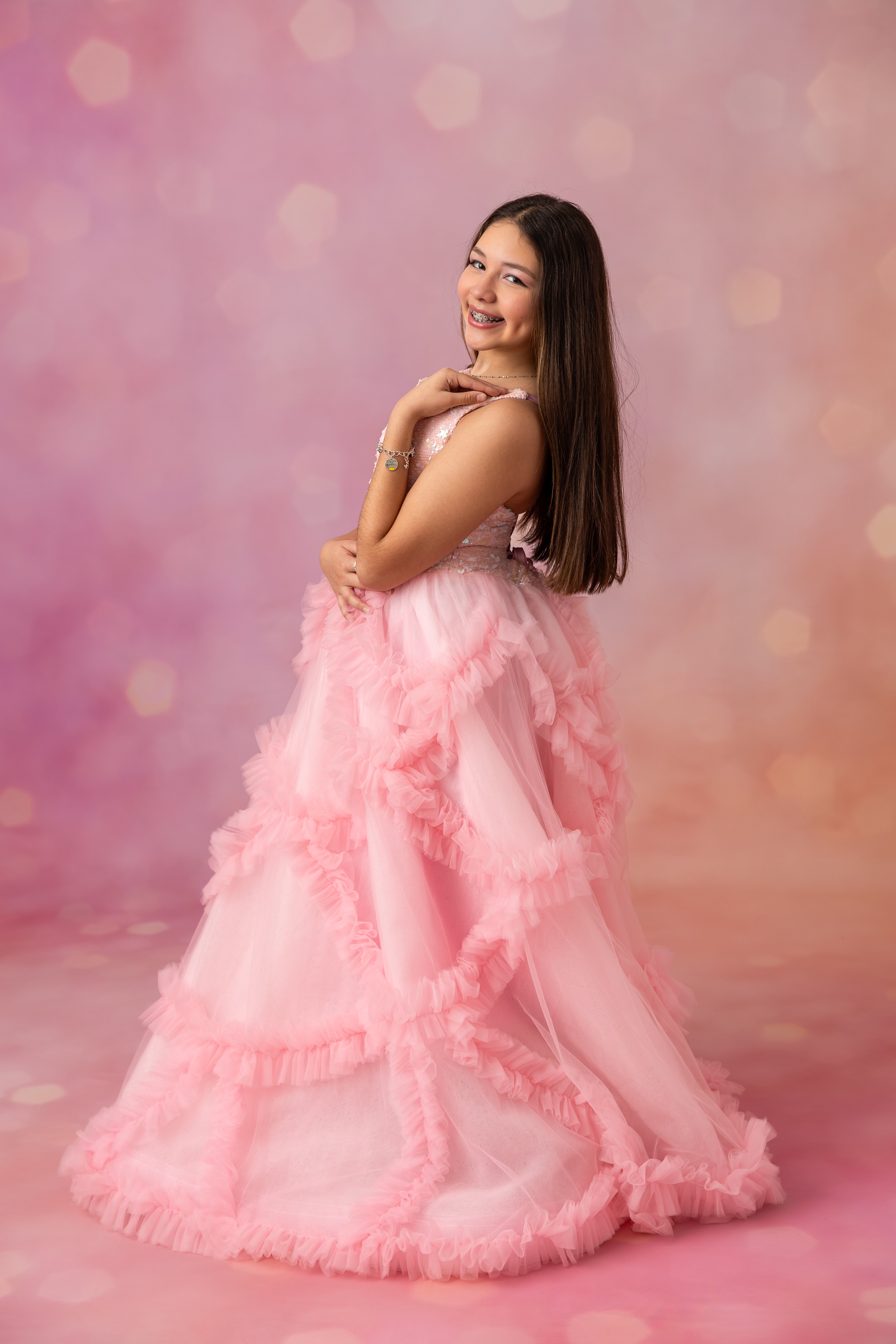 Woman in a pink ruffled gown against a soft pink background