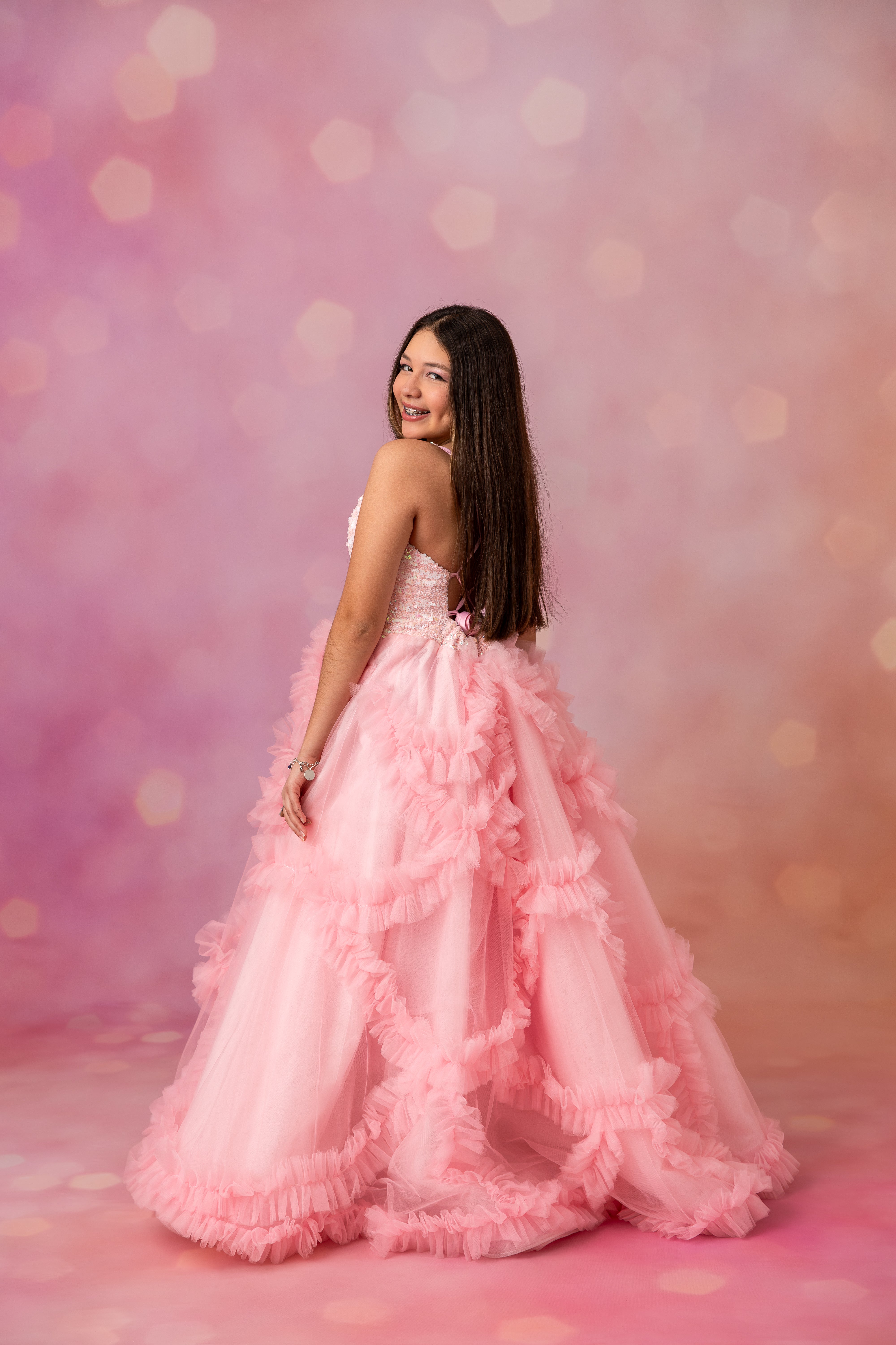 Woman in a pink ruffled dress against a soft pink background