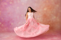 Woman in a pink dress with ruffles on a soft pink background