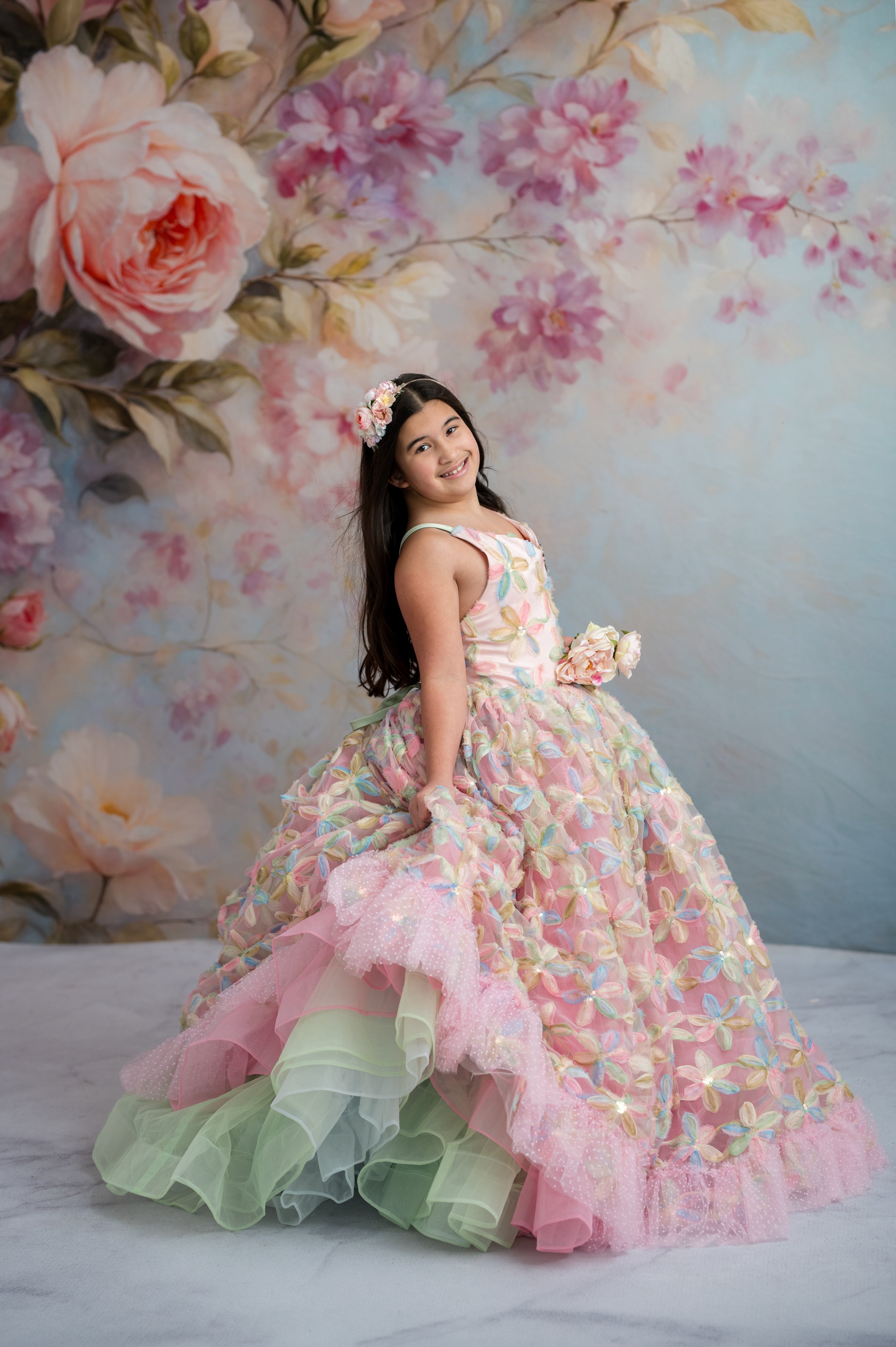Young girl in a floral dress against a floral backdrop