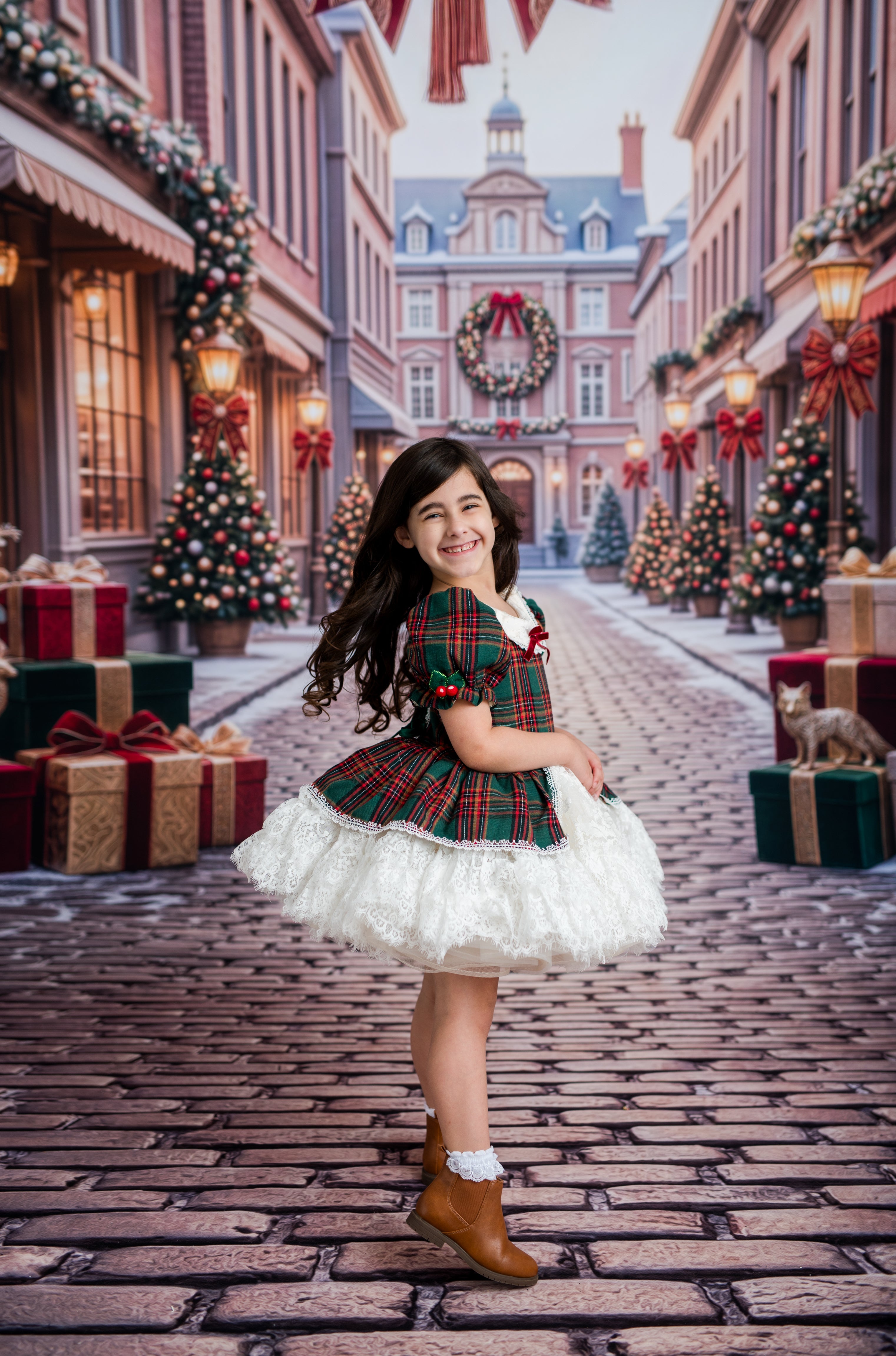 A young girl posing on a cobblestone street decorated for Christmas, wearing a festive green and red plaid dress with a white ruffled skirt and brown boots.