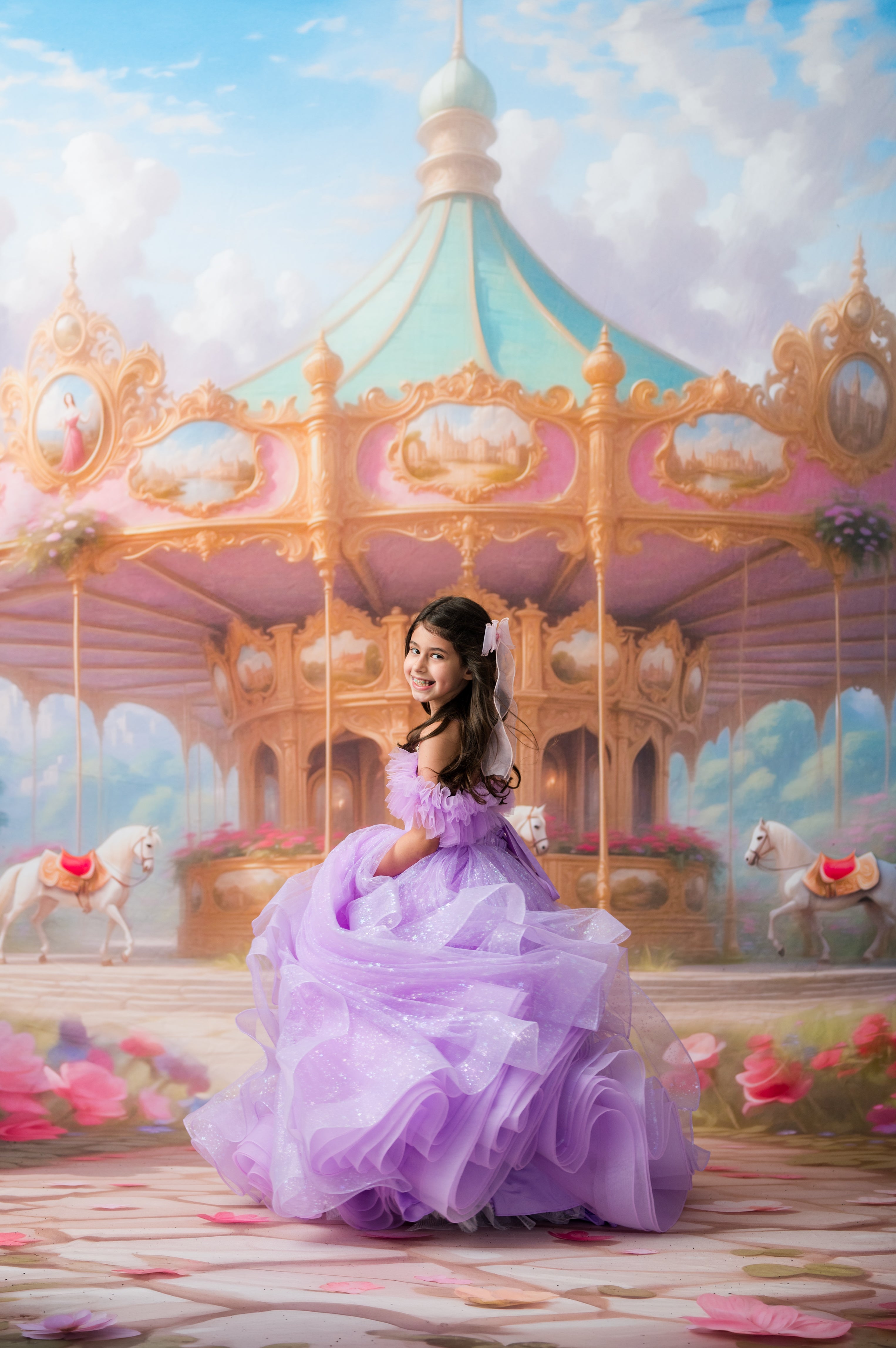 A young woman in a voluminous lavender ball gown sits on a pastel carousel in a dreamy, fantasy-like scene with pink flowers and a soft blue sky.