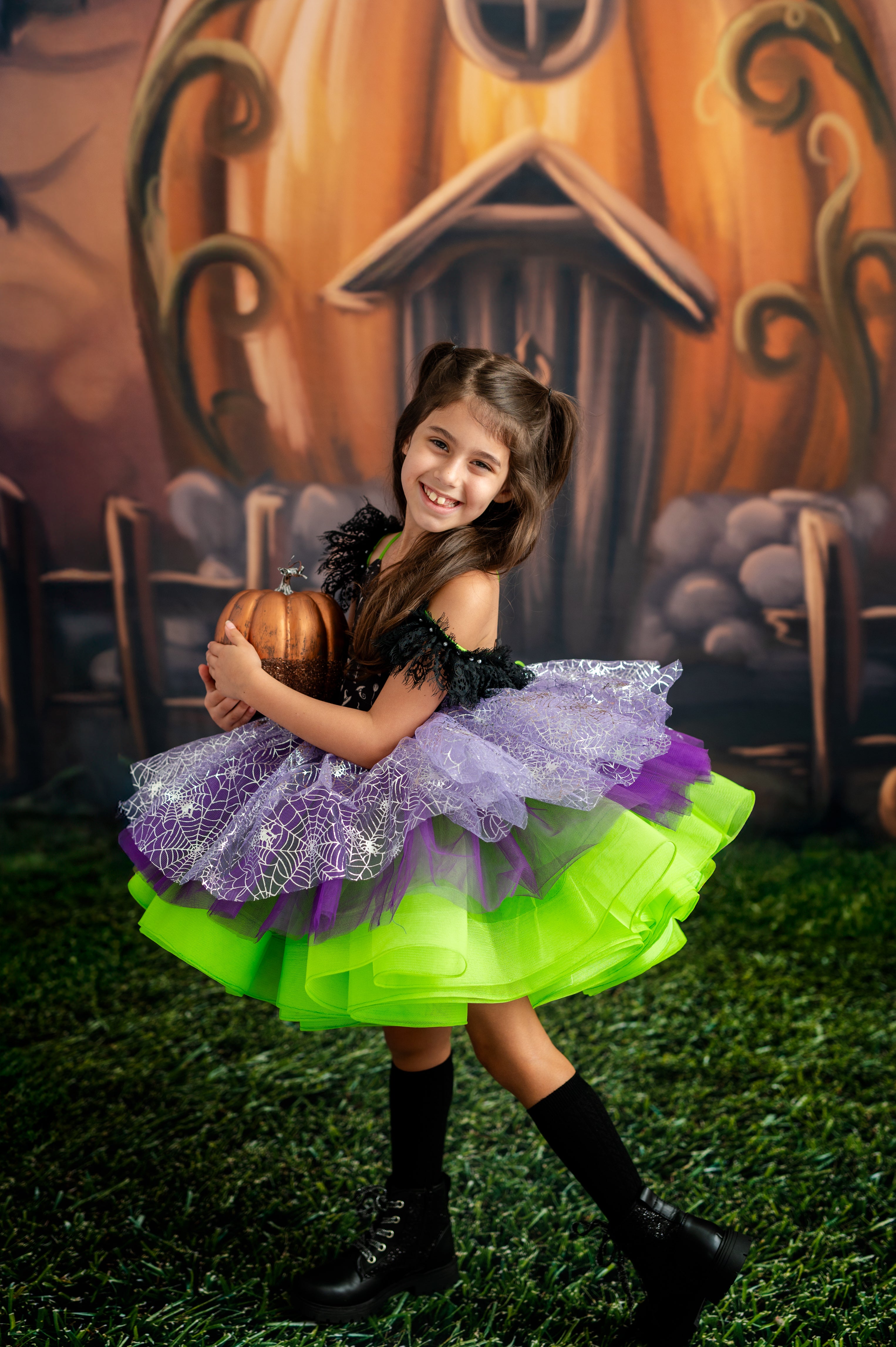 Young girl in a Halloween costume with a pumpkin and haunted house backdrop