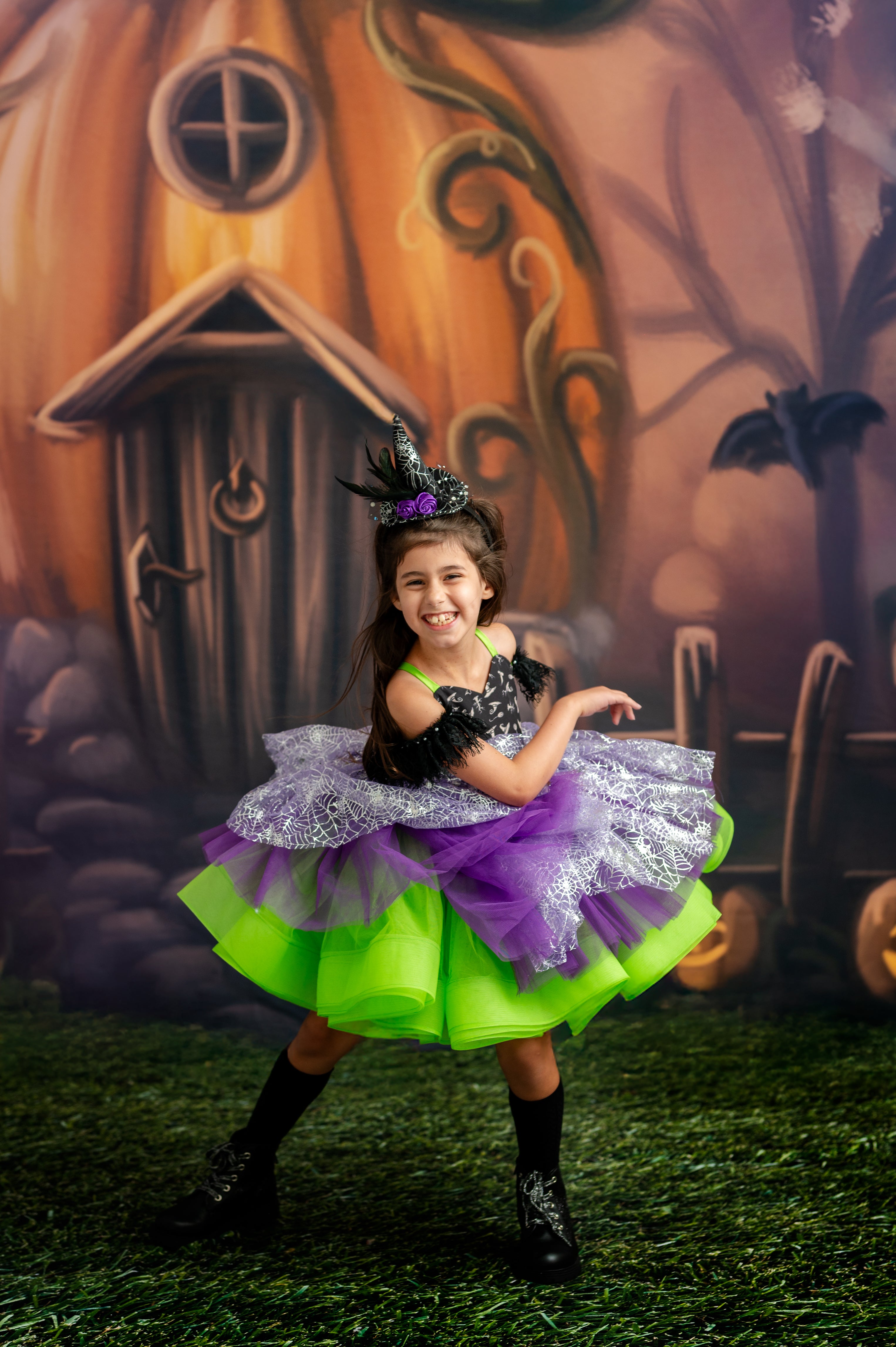 Young girl in a Halloween costume with a decorated pumpkin house in the background