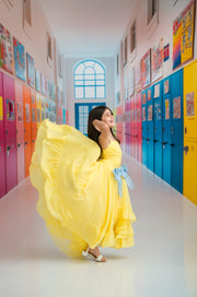 Woman in a yellow dress standing in a colorful school hallway