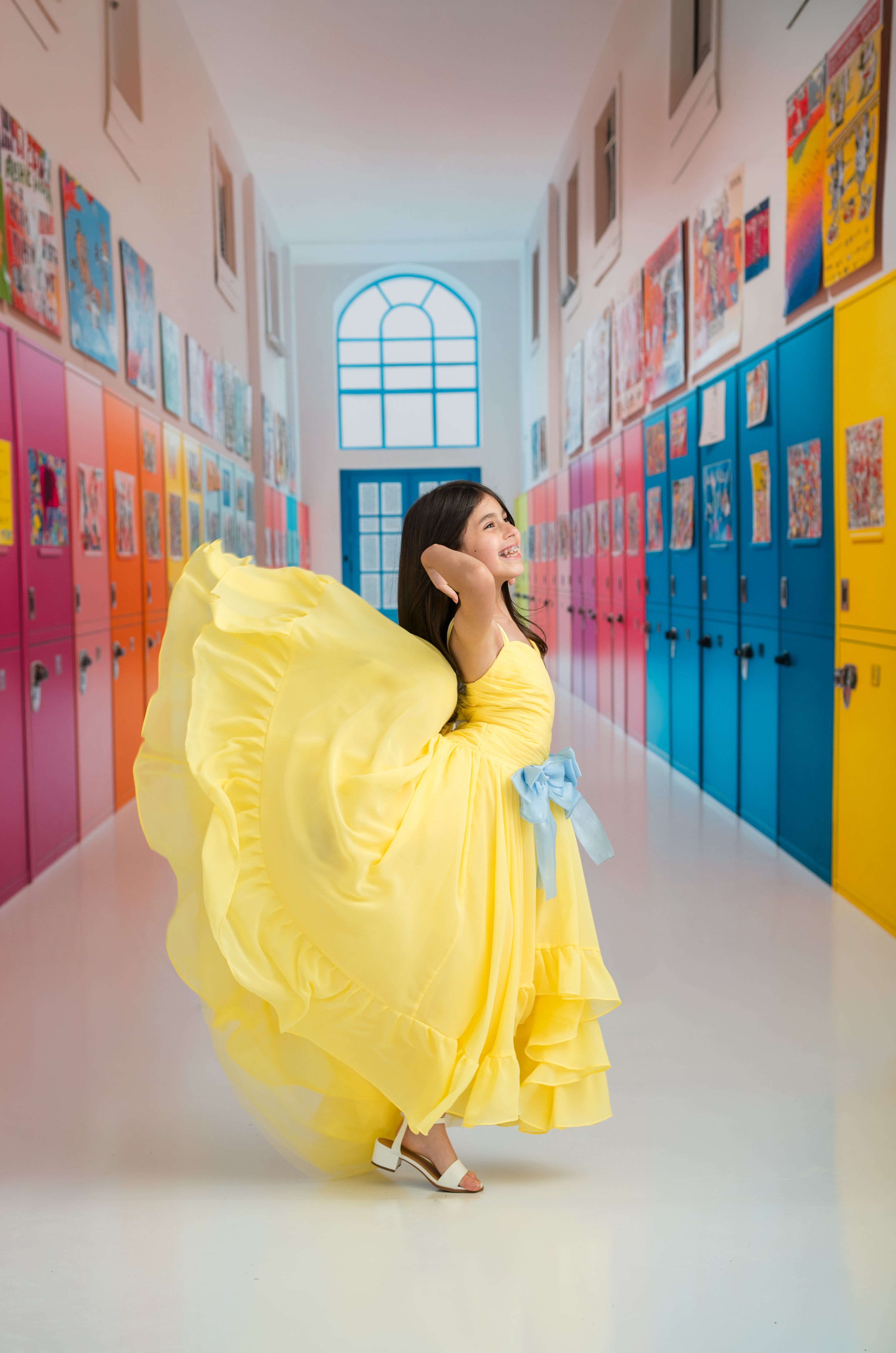 Woman in a yellow dress standing in a colorful school hallway