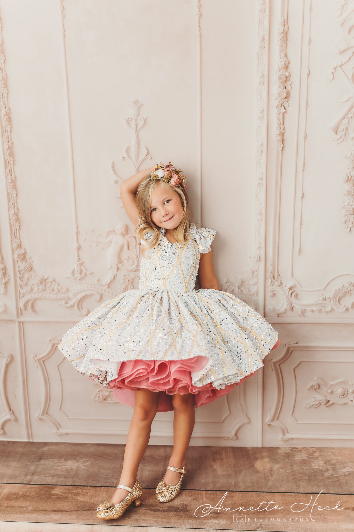 A young girl twirls in a glittering dress with a pink ruffled underskirt, showcasing the vibrant layers.