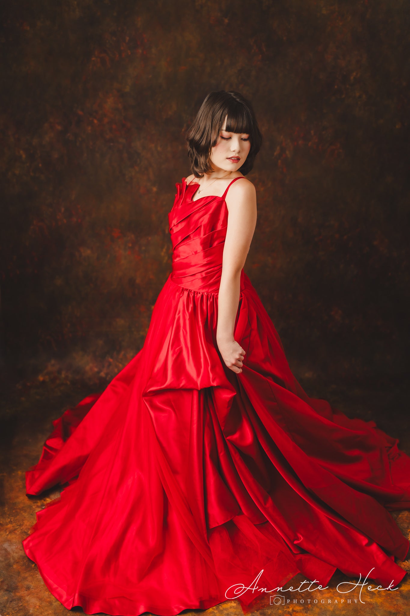 Elegant red satin gown with a flowing skirt and delicate off-the-shoulder sleeves.