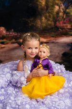 Young girl in a purple dress holding a doll with a yellow dress in a fantasy setting.