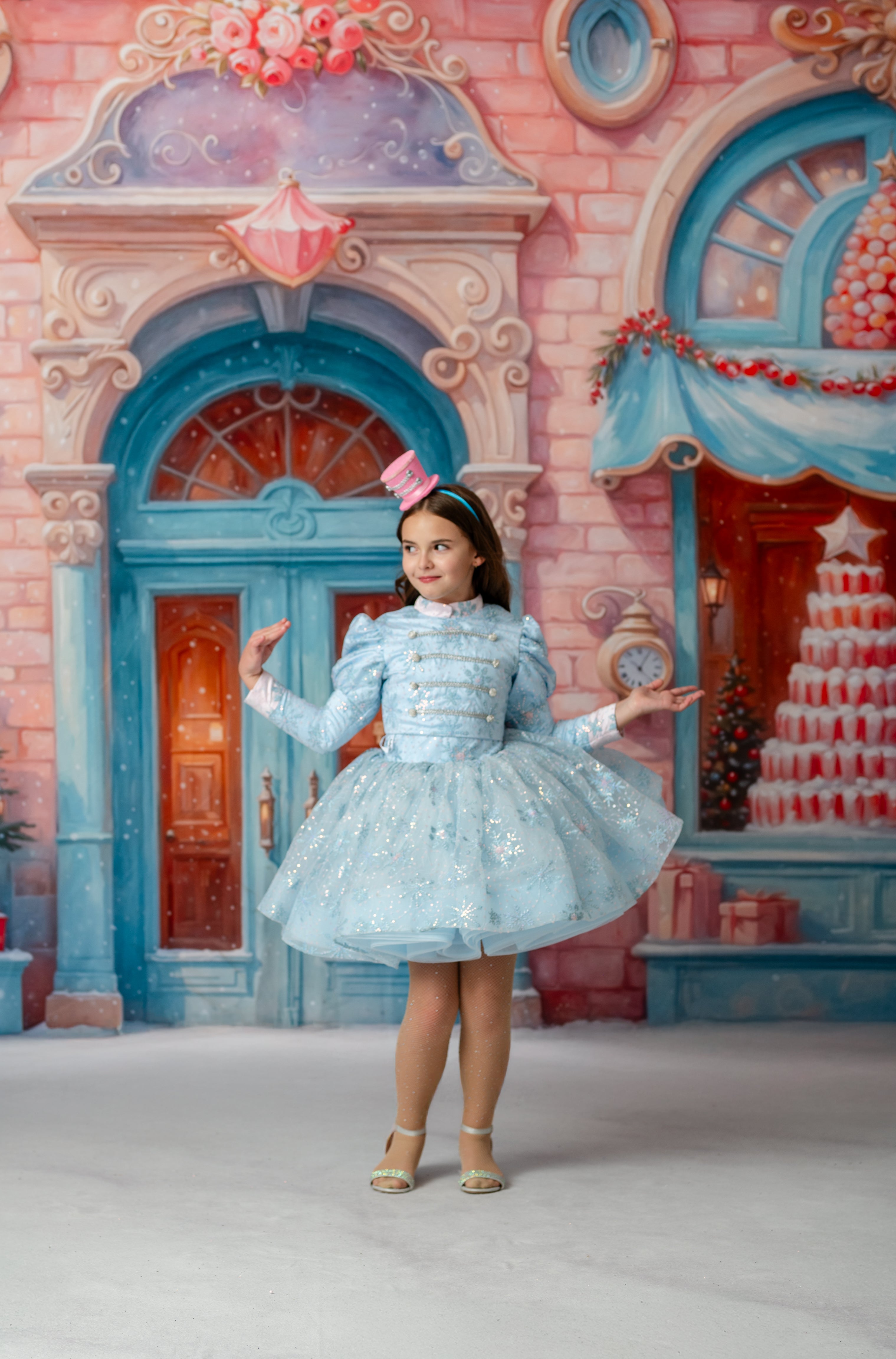 Young girl in a light blue dress standing in front of a colorful, fantasy-style building.