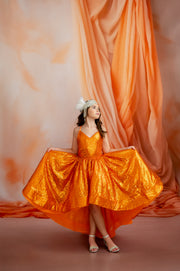 Woman in an orange dress standing in front of an orange curtain