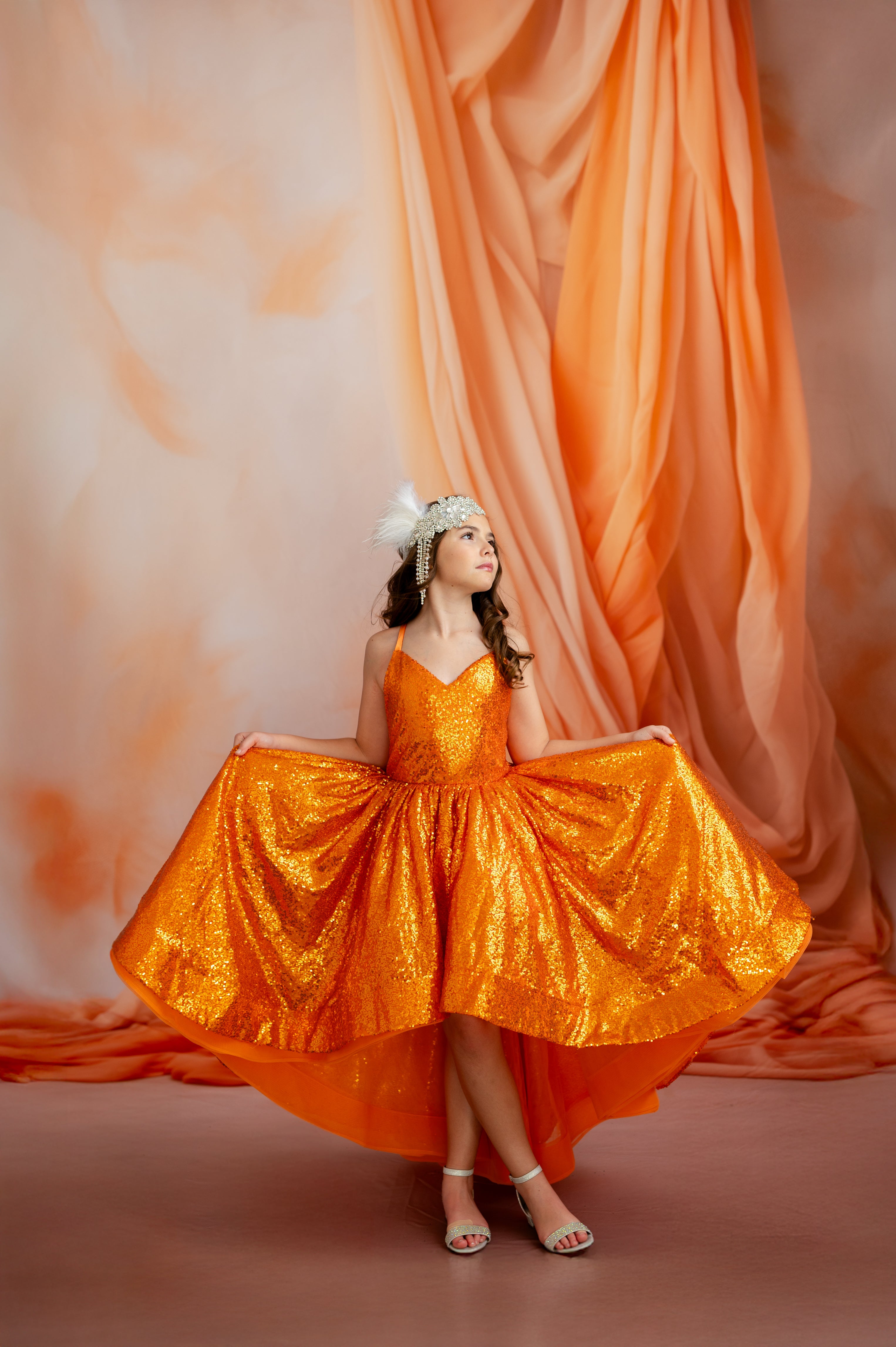 Woman in an orange dress standing in front of an orange curtain