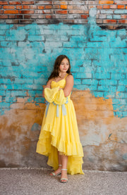 Woman in a yellow dress standing against a textured wall with blue and brown colors.
