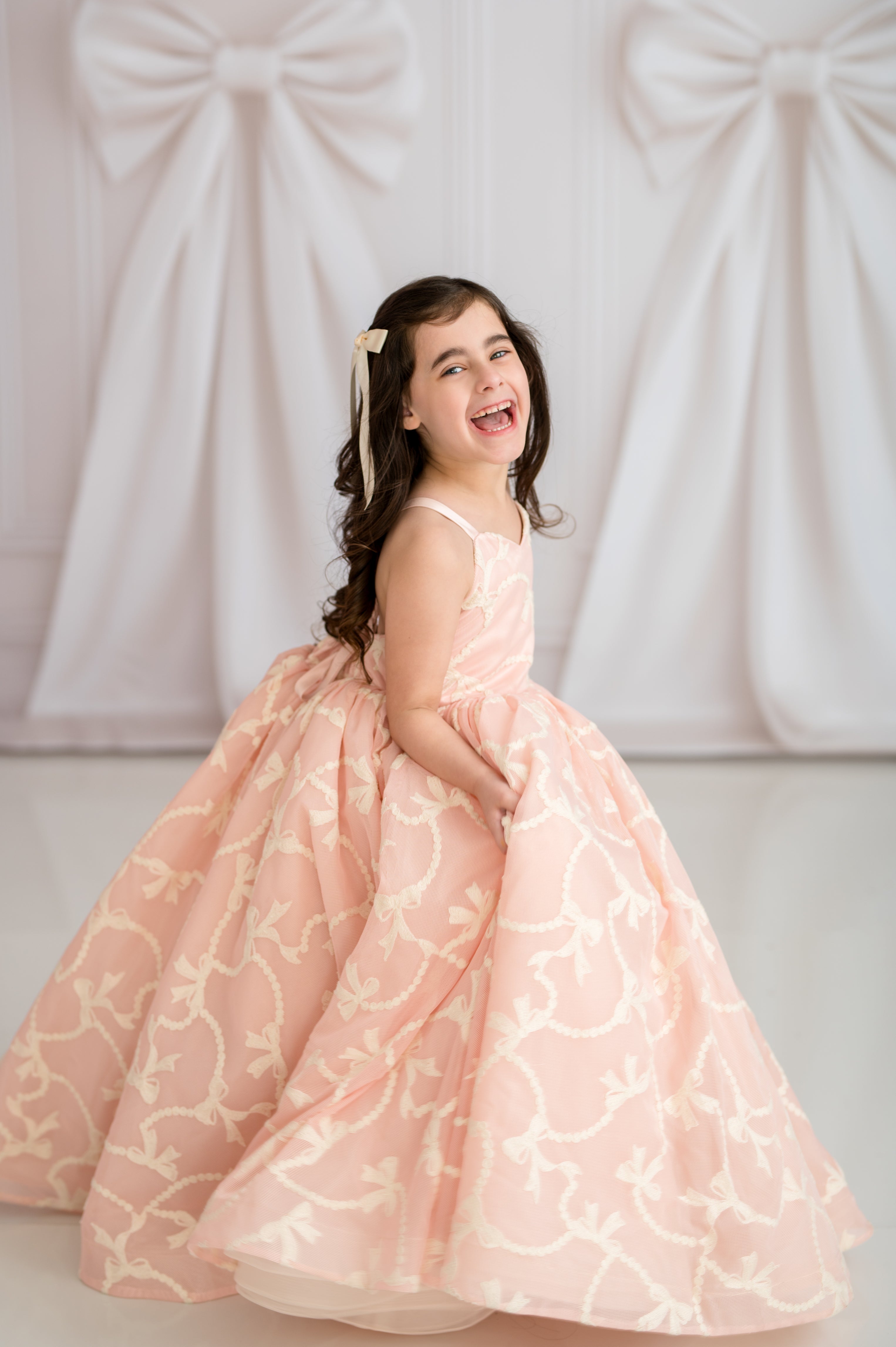 Young girl in a pink floral dress smiling against a white background