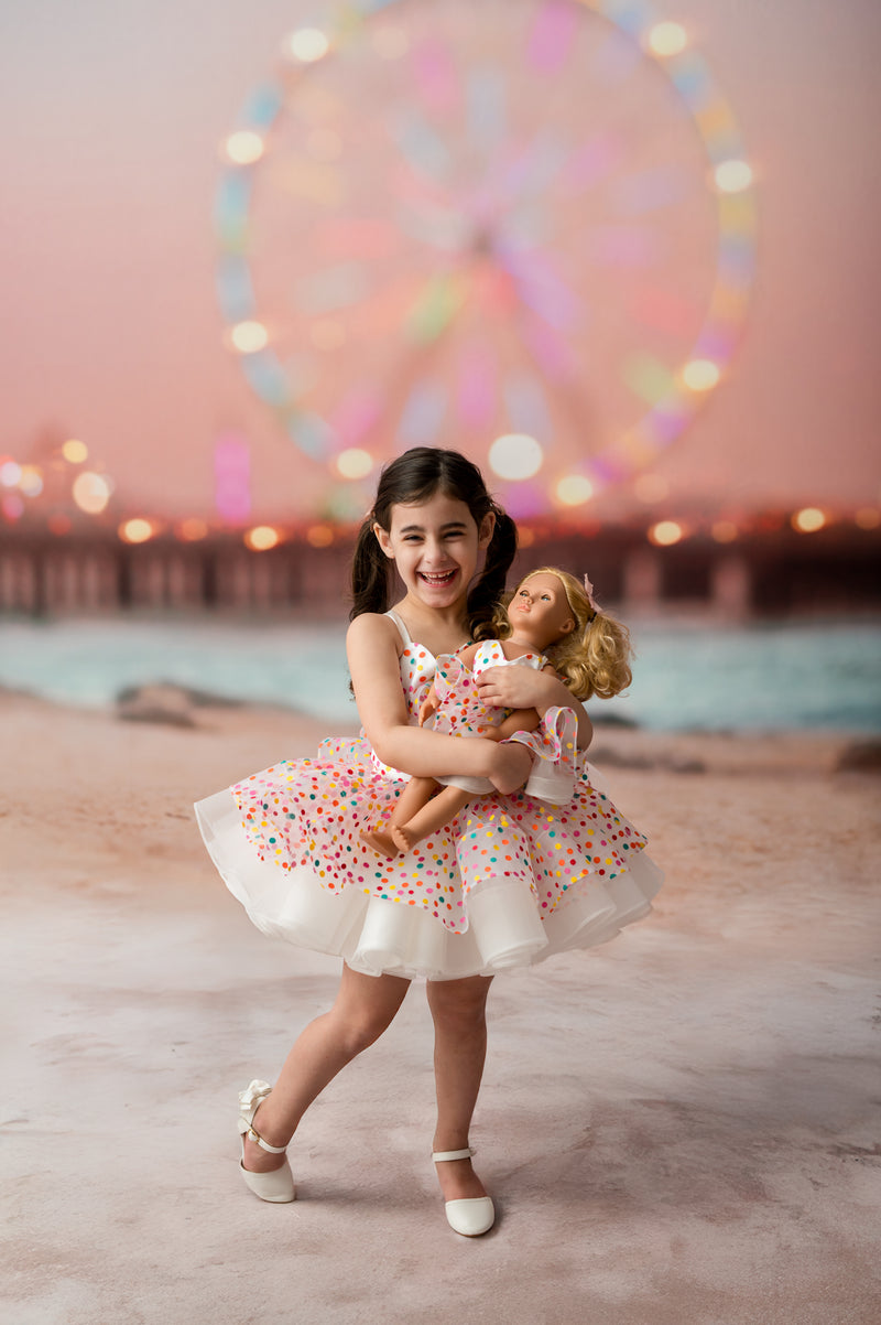 Child-sized polka dot couture dress displayed on white mannequin with gold accents