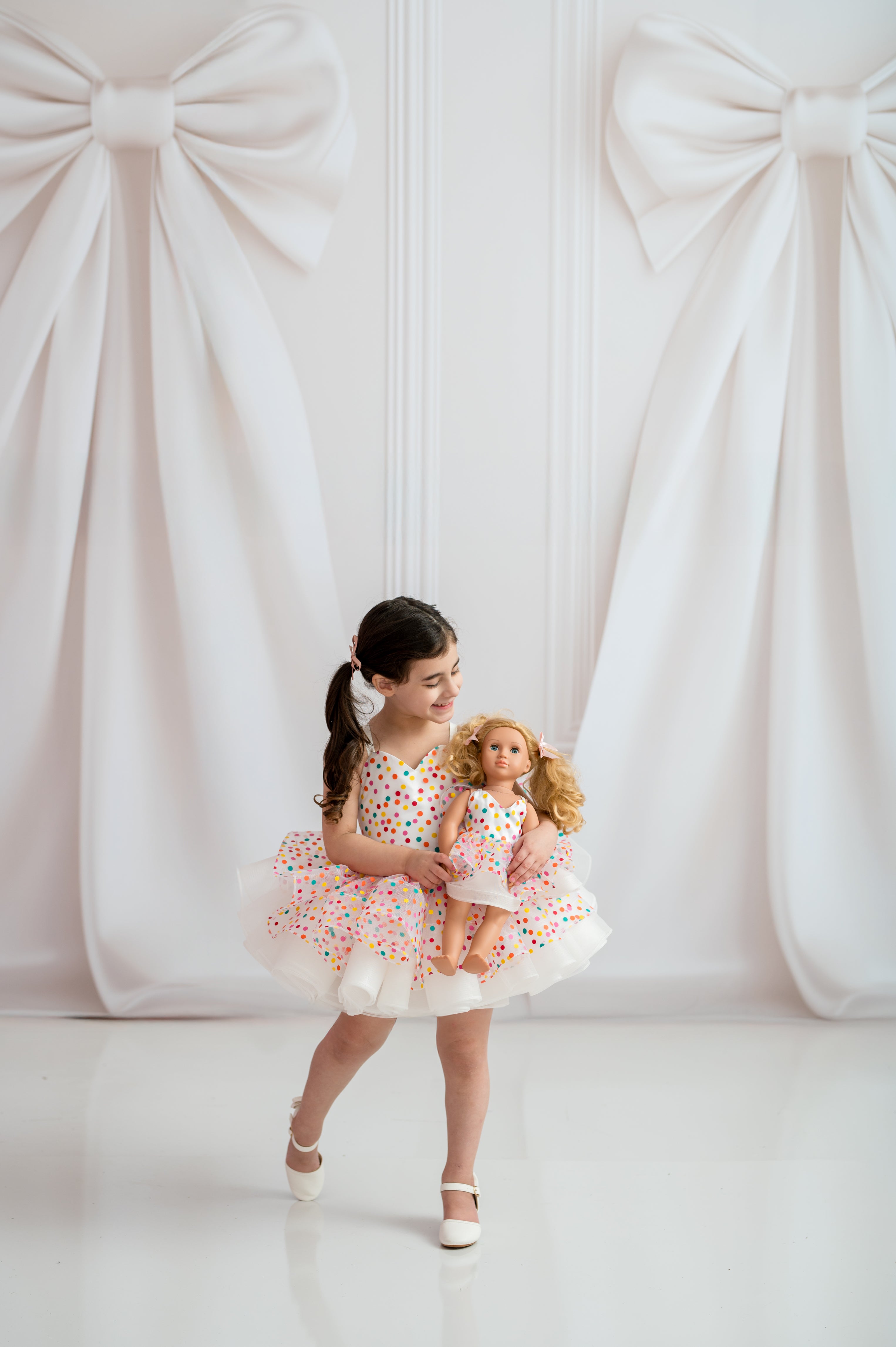Couture toddler dress displayed on gold-accent mannequin in fine art studio