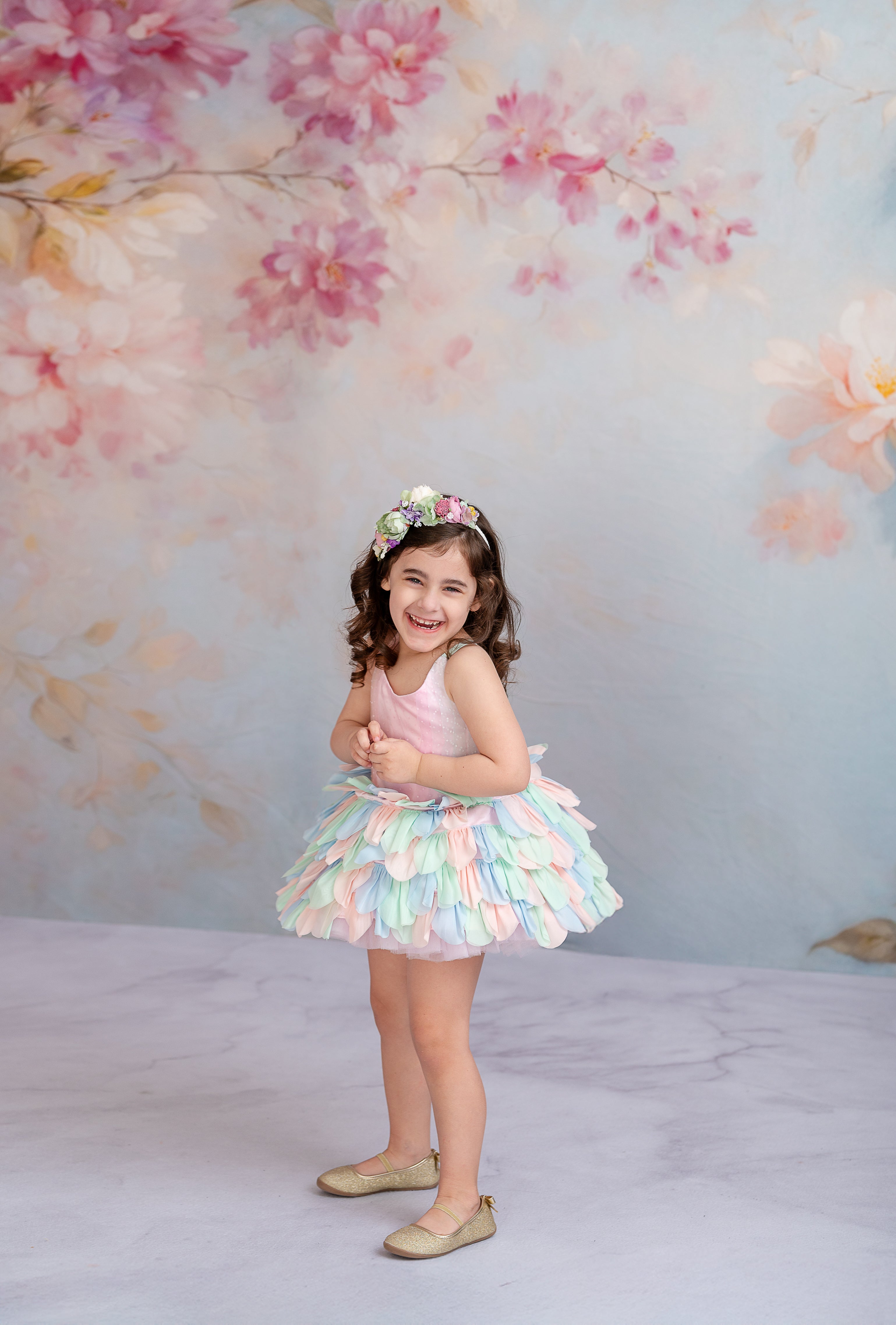 "Fairy-tale inspired children’s gown featuring soft pastel hues and petal layers."
