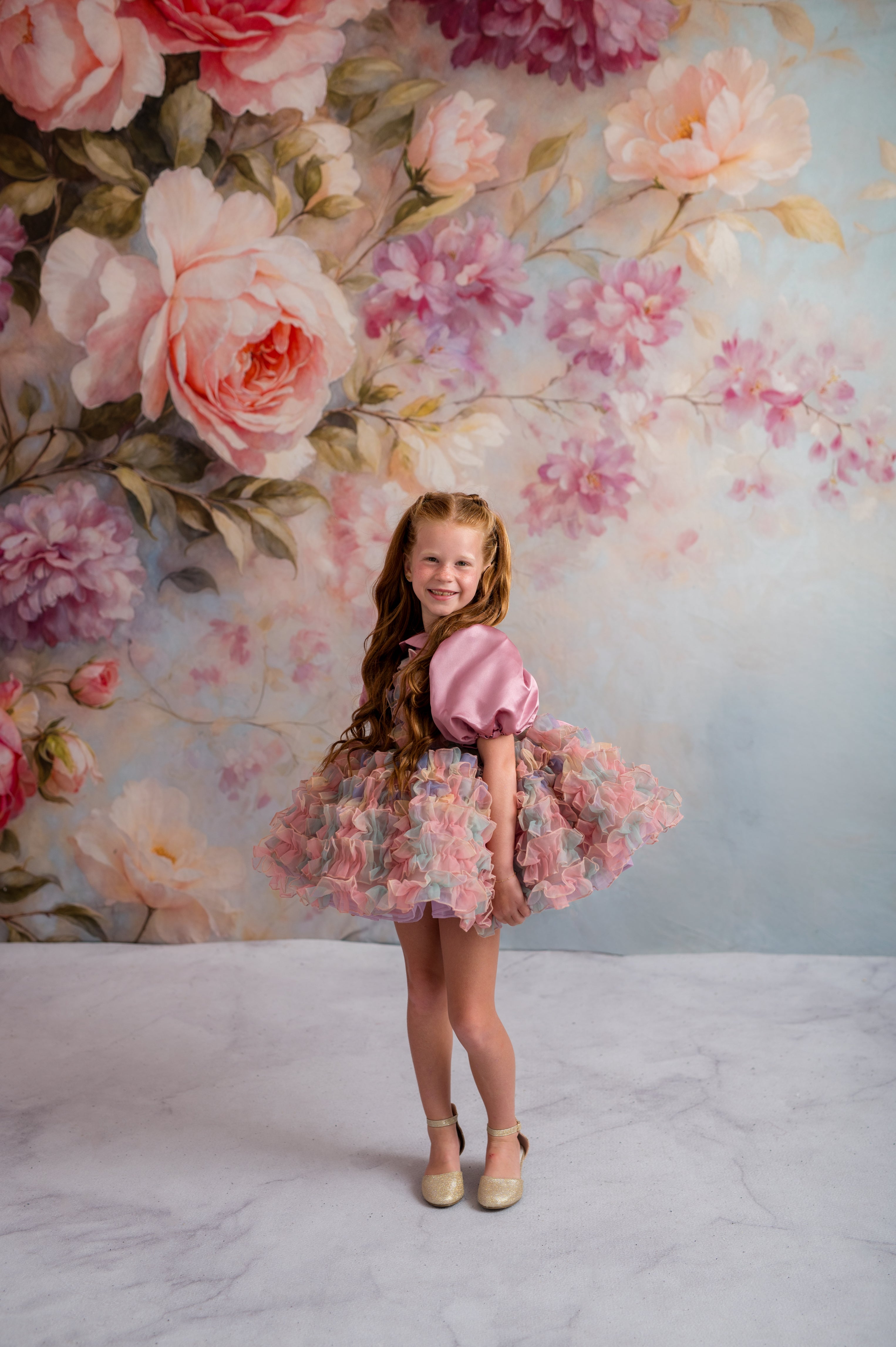 Young girl in a floral dress standing in front of a floral backdrop